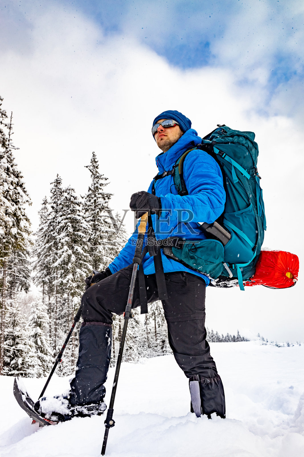 一个背着背包的人在雪地上穿着雪鞋行走，进行冬季徒步旅行。照片摄影图片