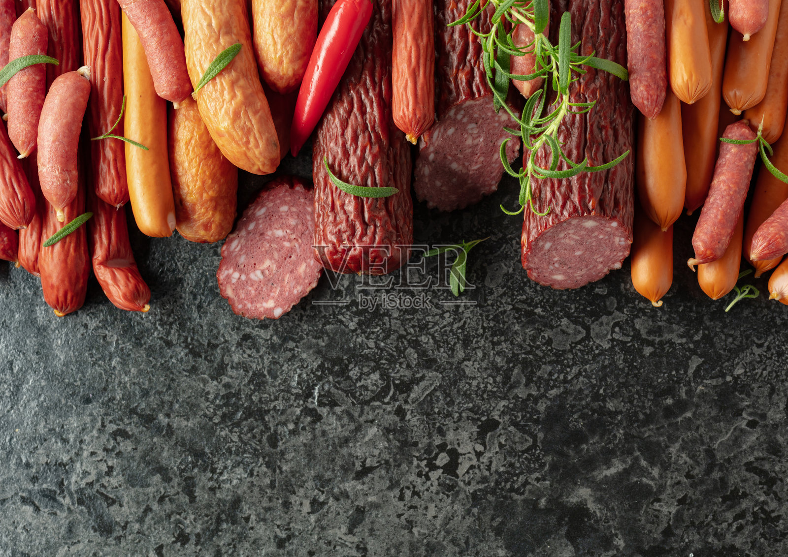 各种干腌和熏制香肠，配有红椒和迷迭香。照片摄影图片