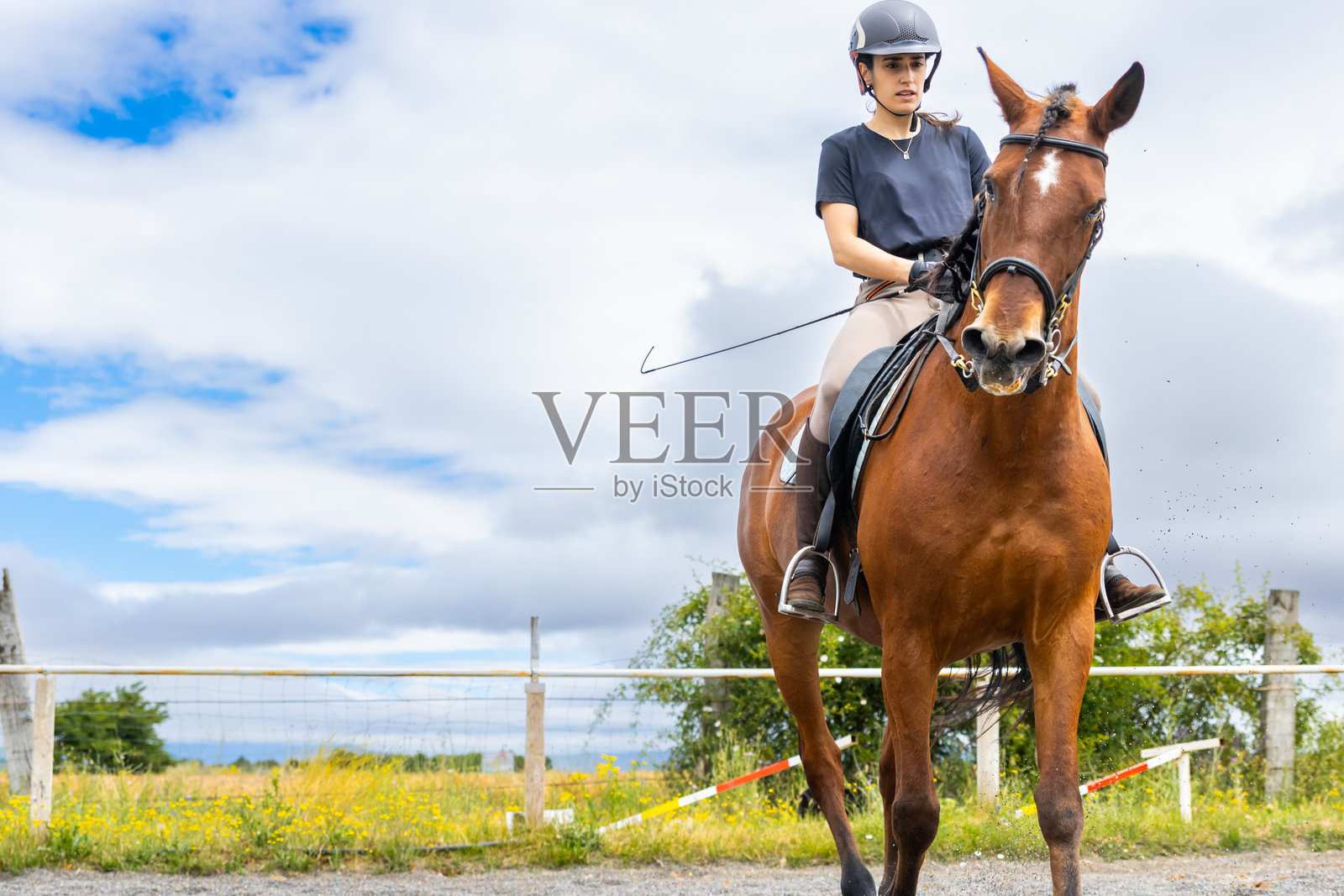 年轻女性在阴天的马场上骑马照片摄影图片