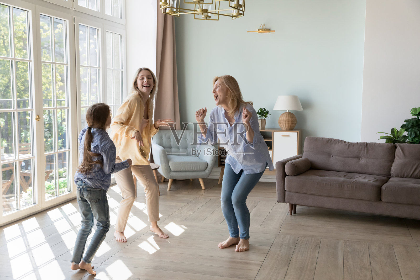 快乐兴奋的年轻妈妈、女儿和充满活力的奶奶一起跳舞照片摄影图片