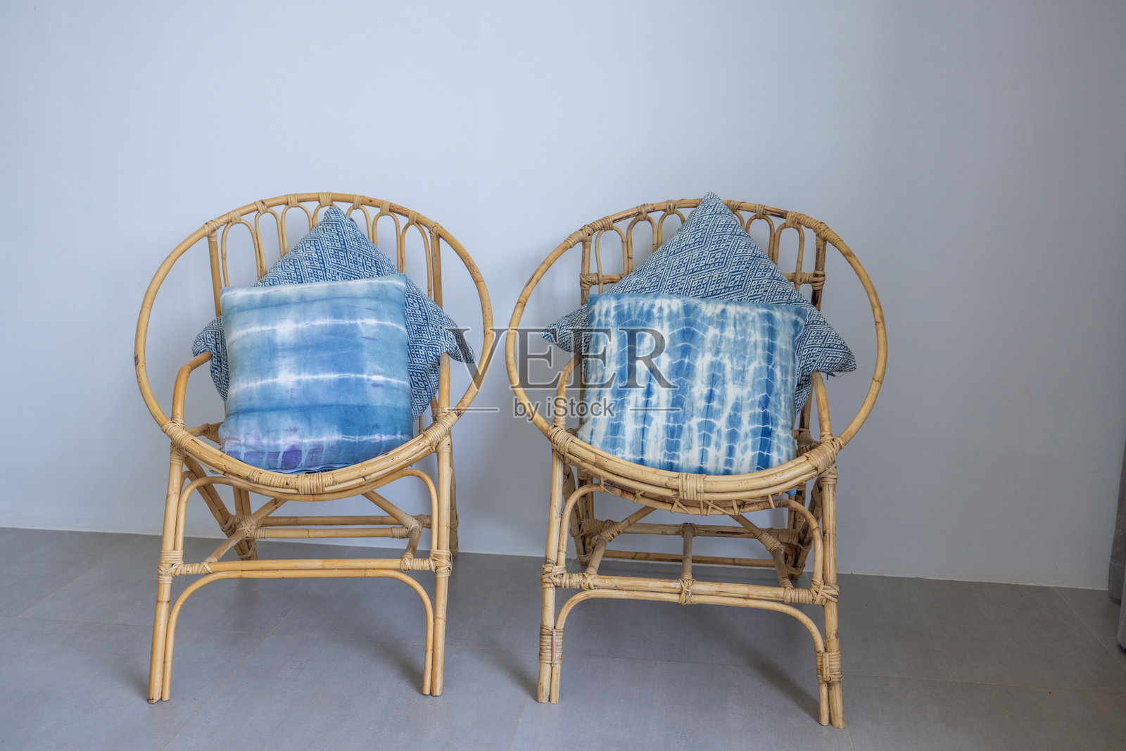 一对带蓝色垫子的藤椅，置于简约环境中照片摄影图片