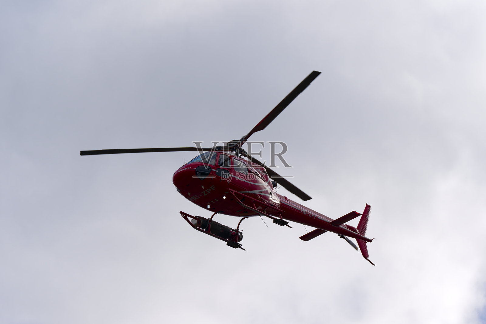 仰望着在冬日抵达瑞士苏黎世克洛滕机场的Aérospatiale AS 350B2 Ecureuil直升机，注册号HB-ZPF。照片摄影图片