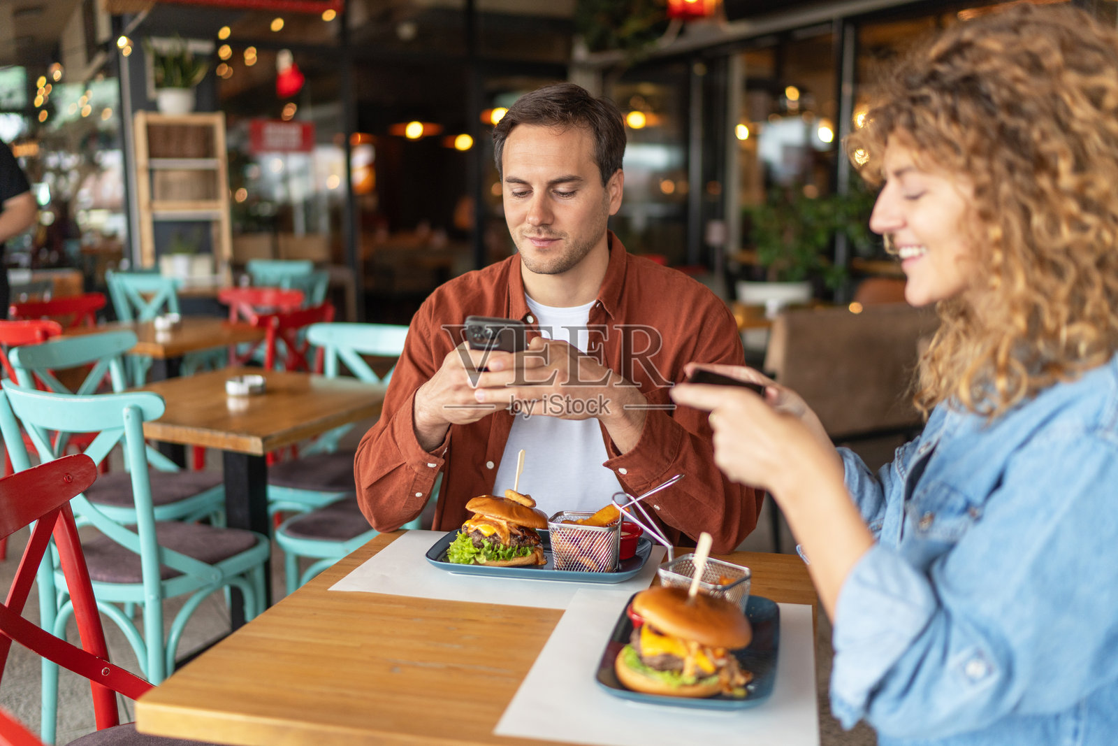 快乐的年轻情侣在餐厅享用汉堡照片摄影图片