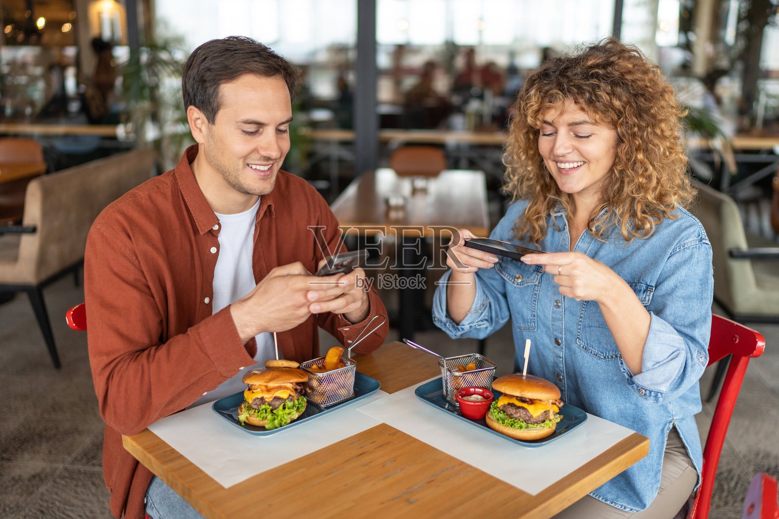 快乐的年轻情侣在餐厅享用汉堡照片摄影图片