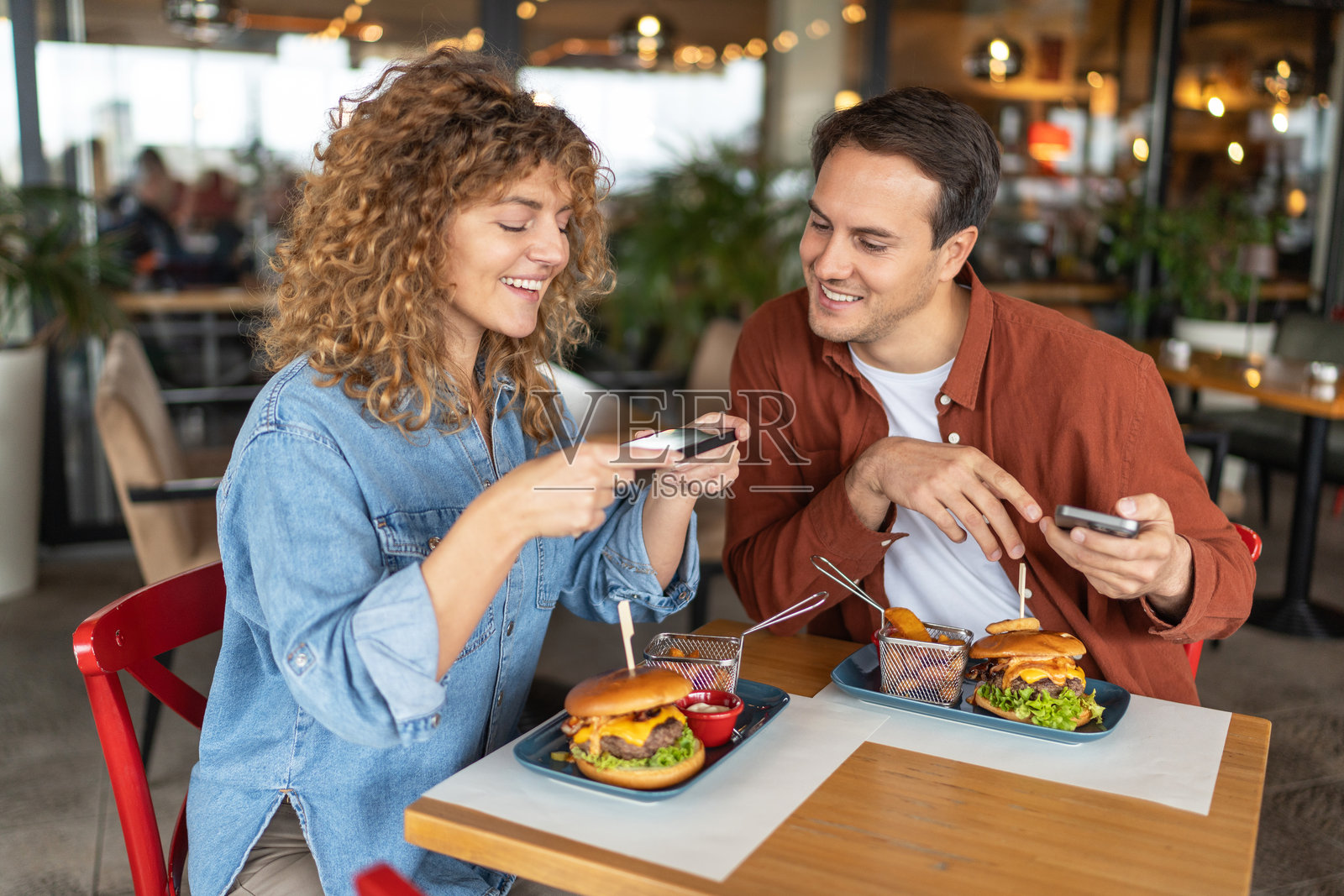 快乐的年轻情侣在餐厅享用汉堡照片摄影图片