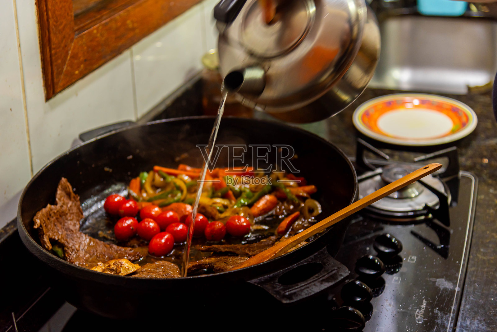 在家庭厨房中准备的洋葱和红番茄牛排。照片摄影图片
