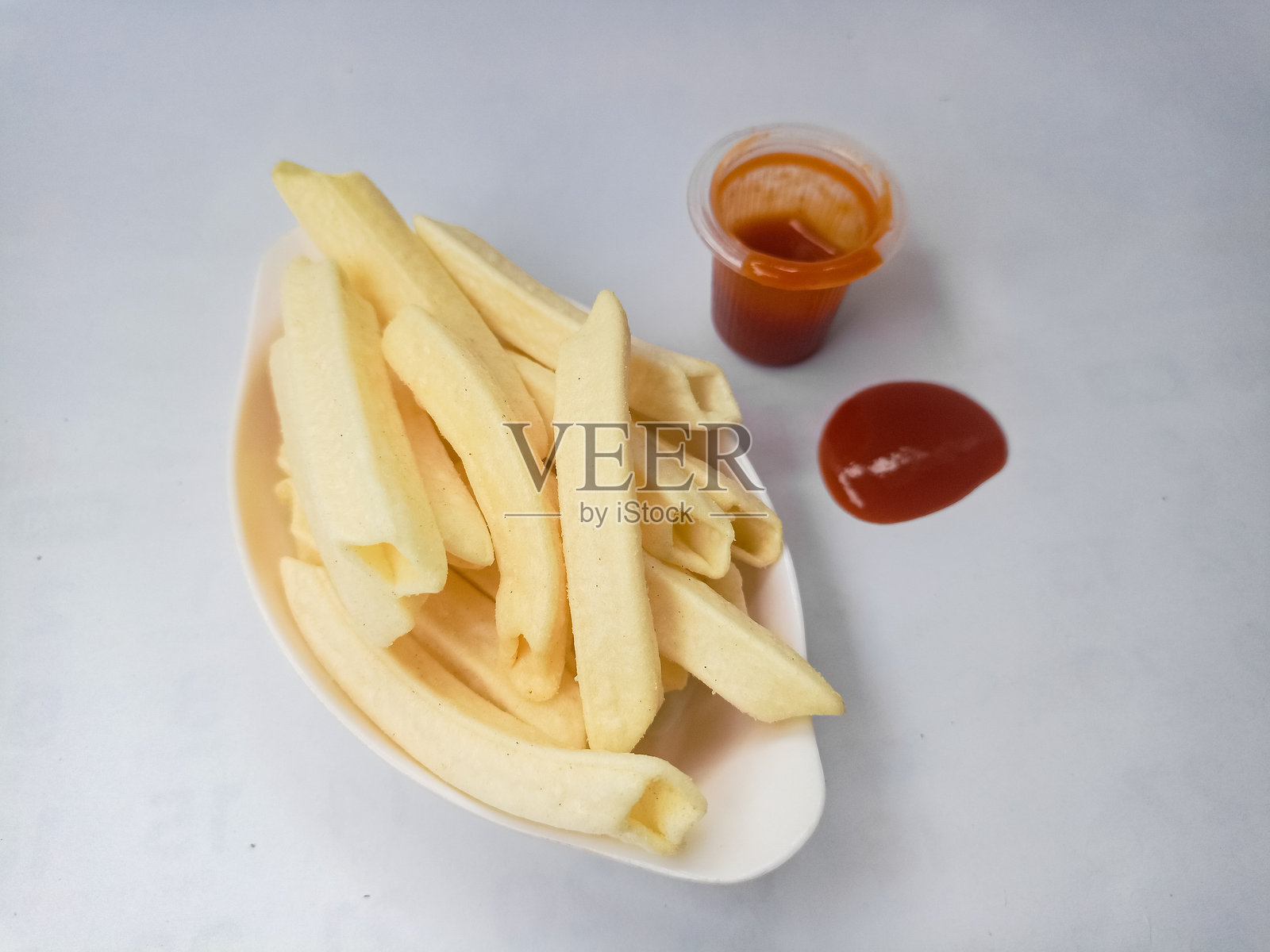 脆脆的土豆条，形似薯条，配有一小容器的辣番茄酱。照片摄影图片