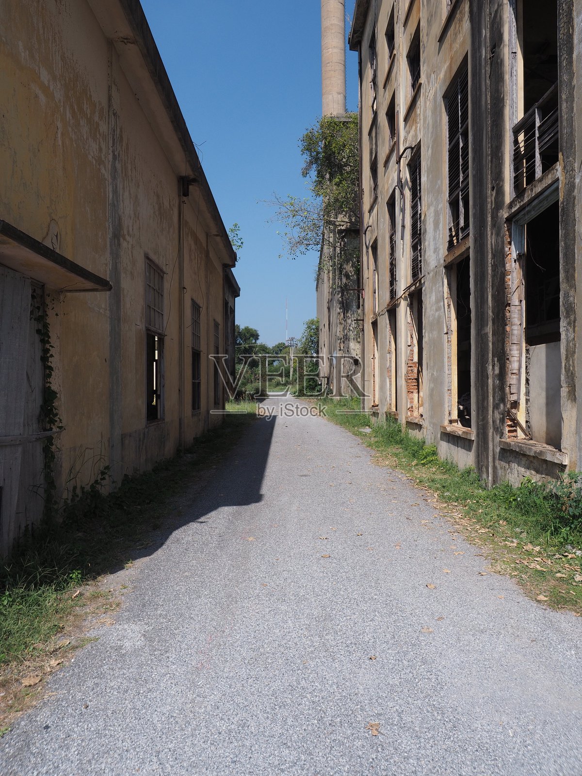 废弃工业建筑之间的狭窄巷道在蓝天之下照片摄影图片