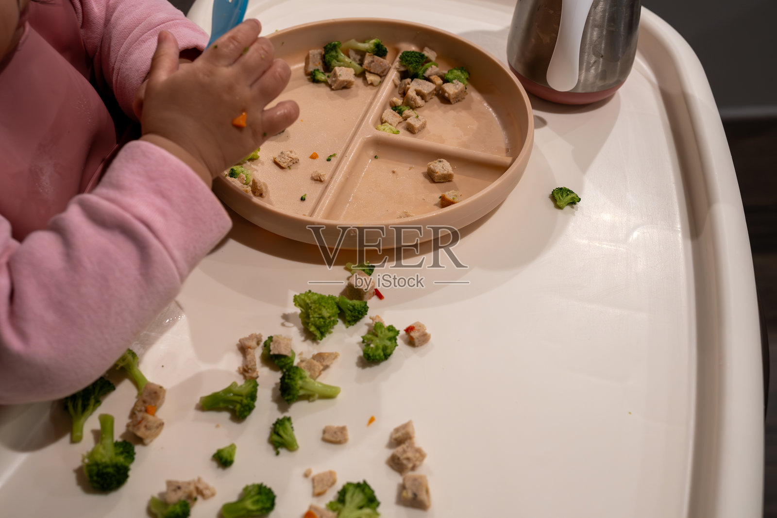 小孩在家晚餐时享用分隔盘中的西兰花和鸡肉。照片摄影图片