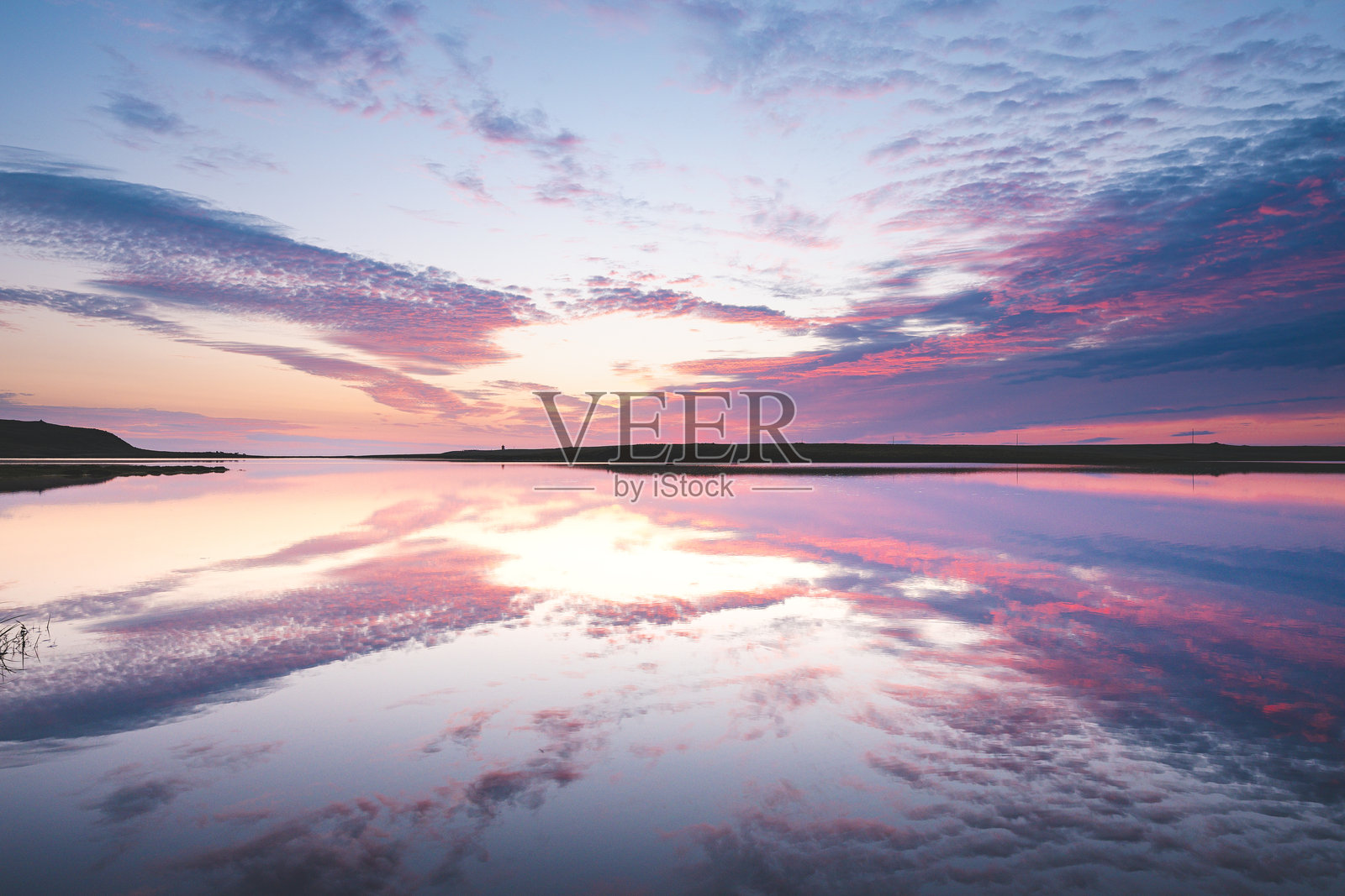 冰岛斯奈法尔斯半岛的壮丽日落，鲜艳的粉色和紫色在平静的水面上完美反射。格伦达菲厄泽附近宁静而令人叹为观止的景色。照片摄影图片