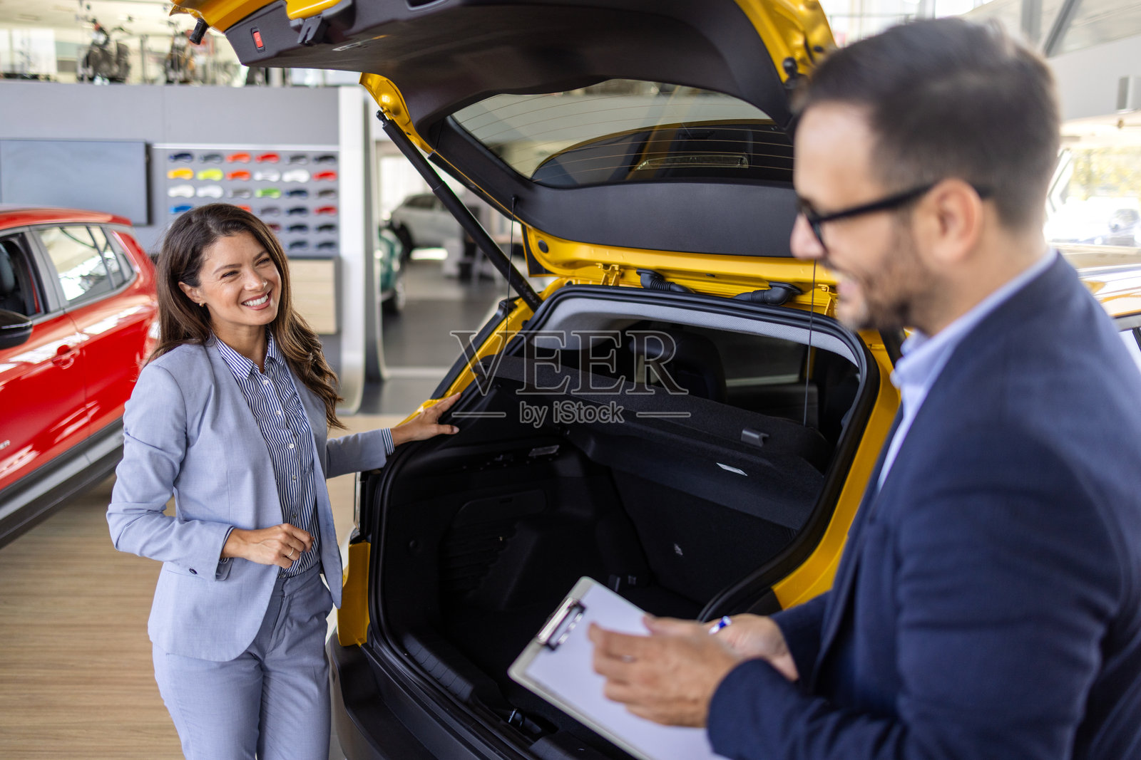 汽车销售经理在豪华汽车经销店向一位白人女性买家展示汽车。购车概念照片摄影图片