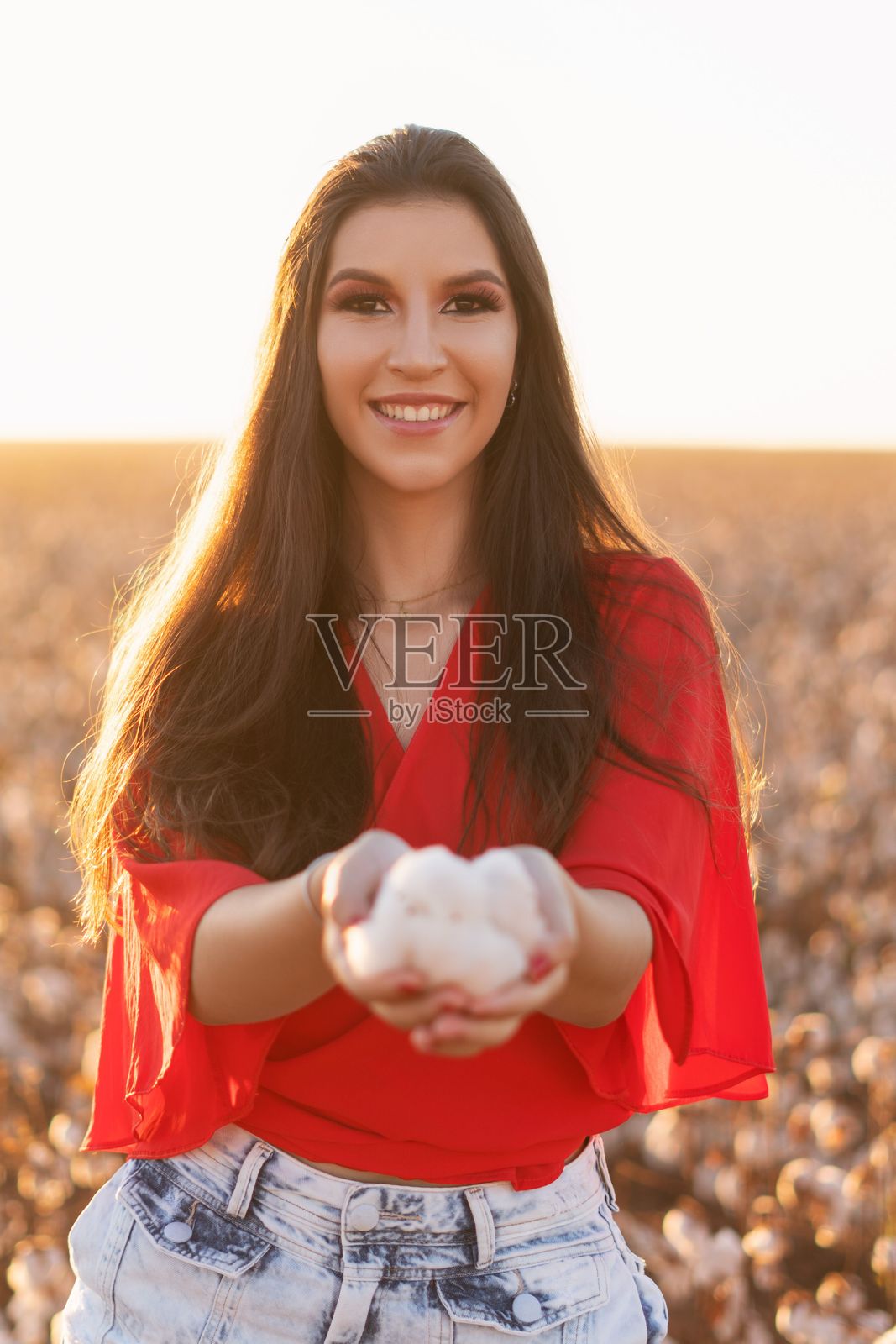 年轻女性在阳光明媚的田野中拿着棉花照片摄影图片
