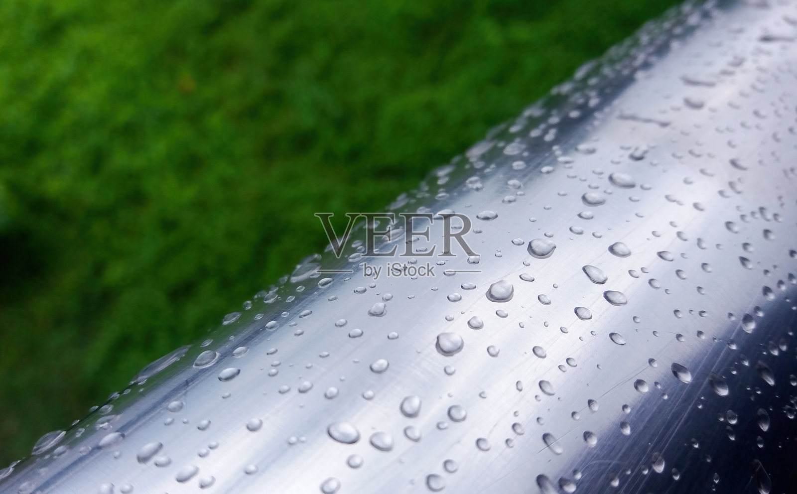 户外钢栏杆上紧贴着的雨滴特写照片。照片摄影图片