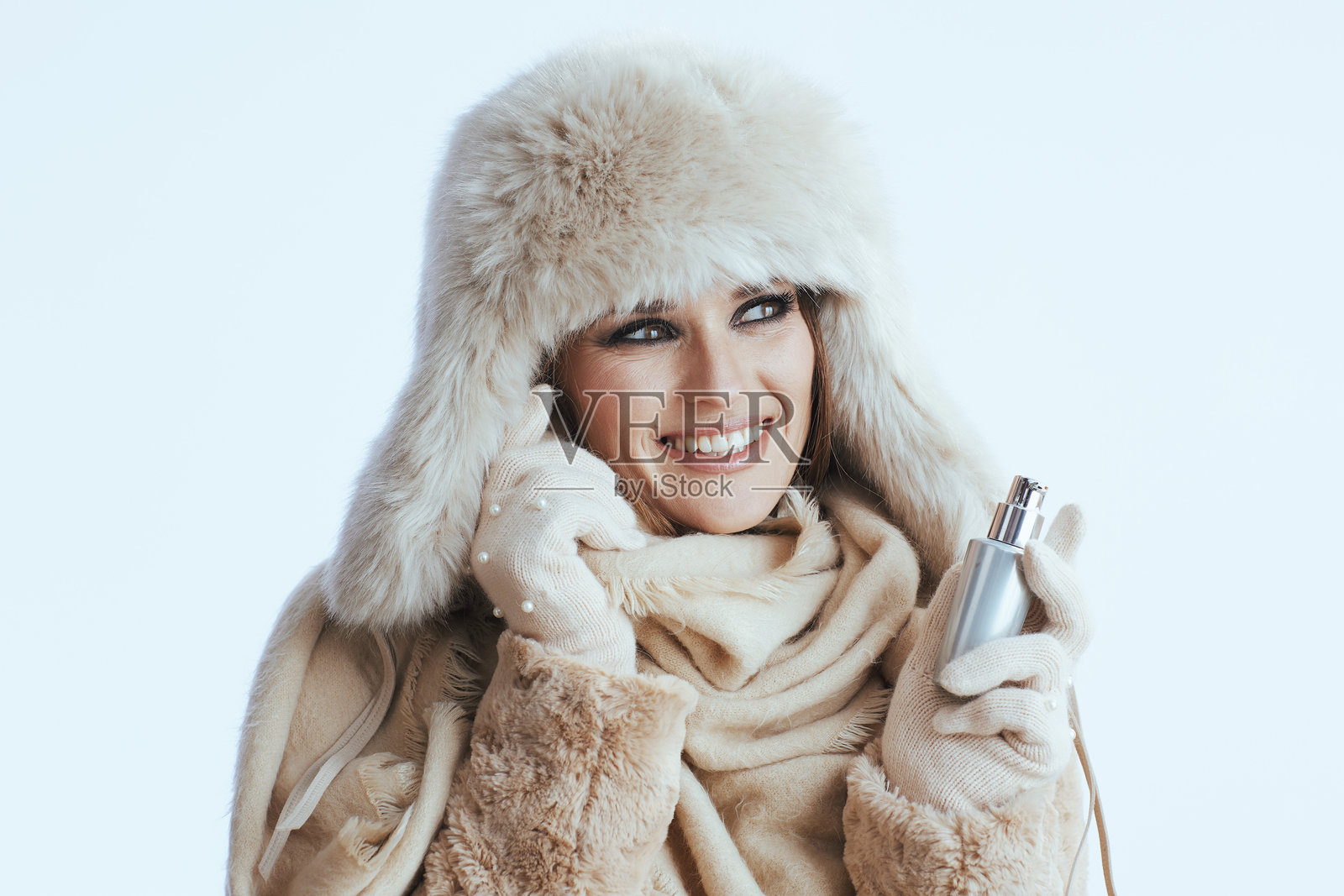 微笑的现代女性穿着冬天的大衣，戴着白色的毛皮帽子照片摄影图片