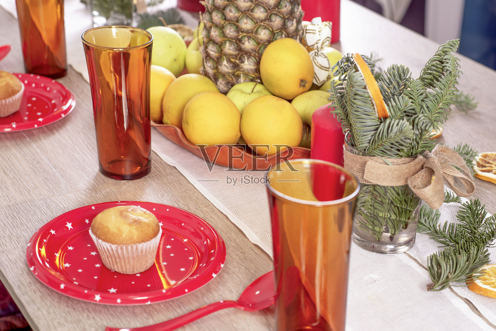 圣诞节日餐桌上装饰着蜡烛、圣诞树枝、桔子干、糖果和水果，选择性集中。舒适的房子用手工制作的物品装饰节日。圣诞装饰照片摄影图片
