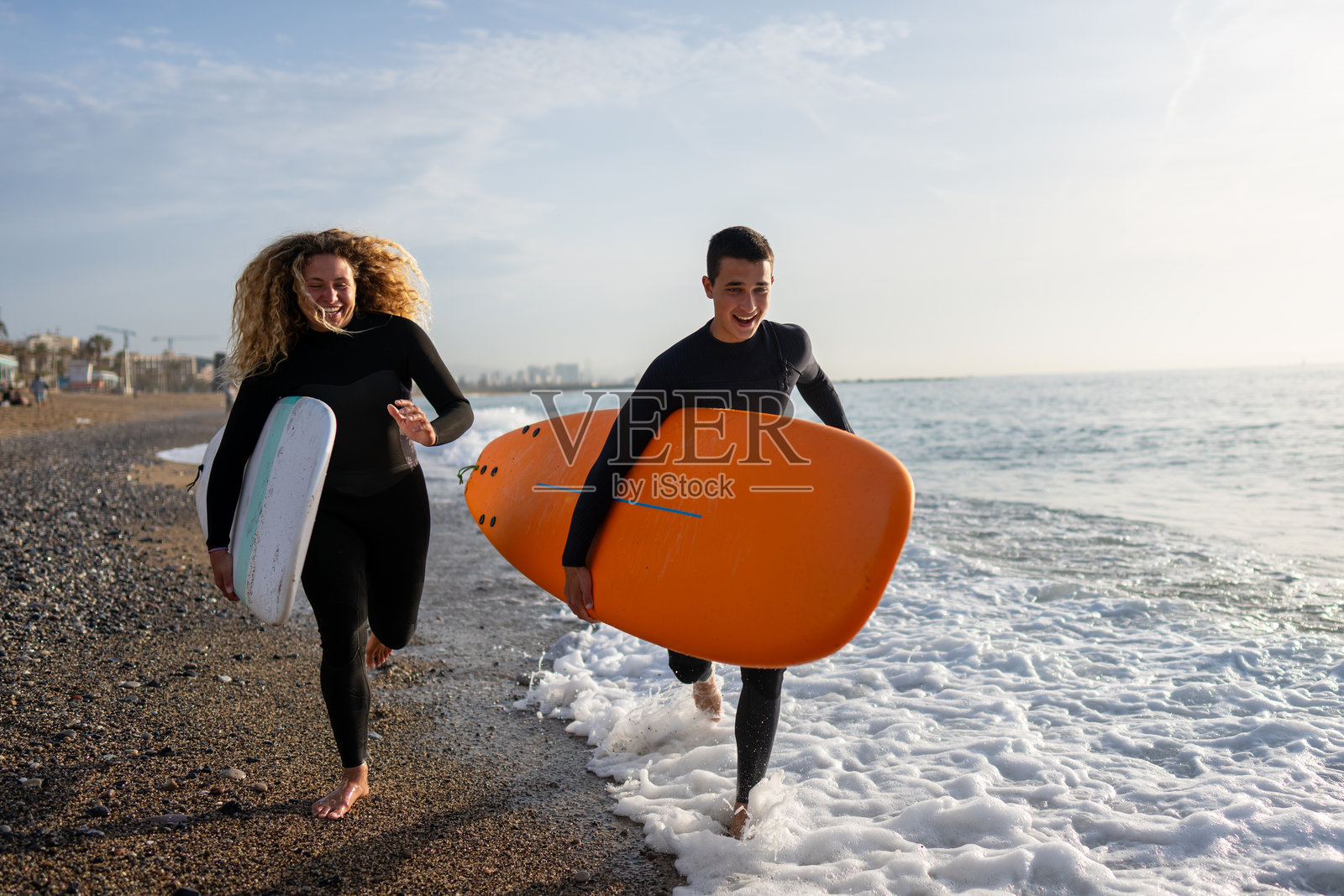 快乐的年轻情侣急忙赶去冲浪，手里拿着冲浪板。冲浪，运动，度假照片摄影图片