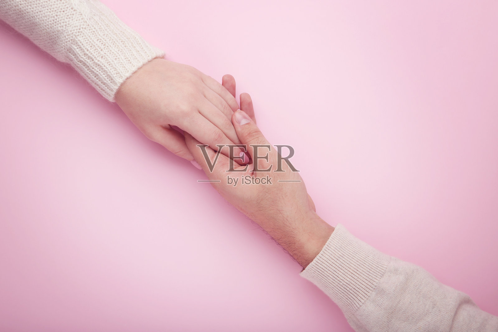 粉色背景上男女手相握照片摄影图片