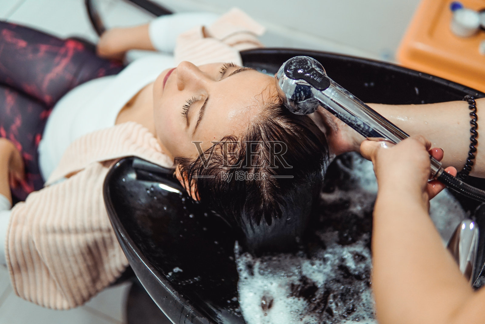 女性在美容院由美发师洗头。照片摄影图片