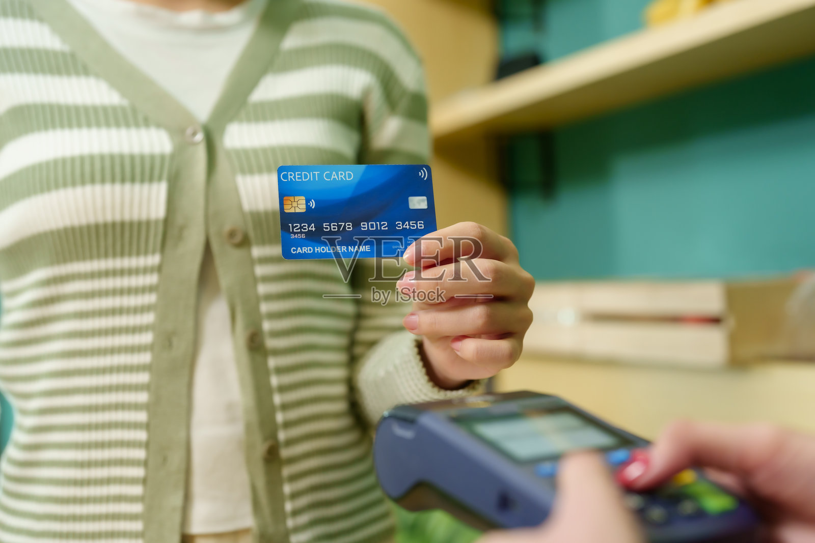 年轻的白人女性顾客手持信用卡，准备在水果店进行无现金购物。电子支付提升了便利性。当地商家正在采用现代金融科技。照片摄影图片