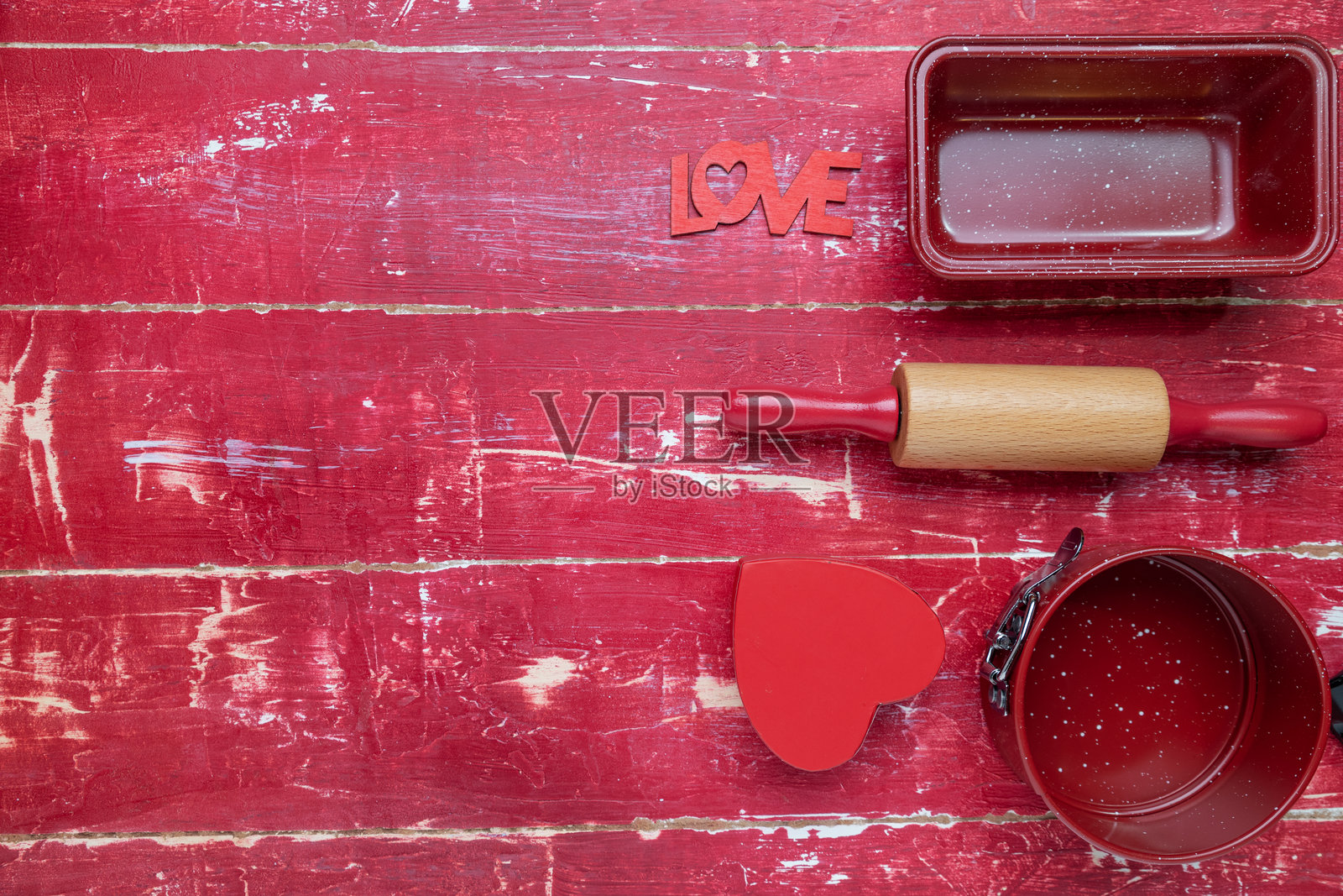 红色木质背景上的擀面杖、饼干切模和面粉。心形和切菜板。俯视图。留有文本空间。照片摄影图片