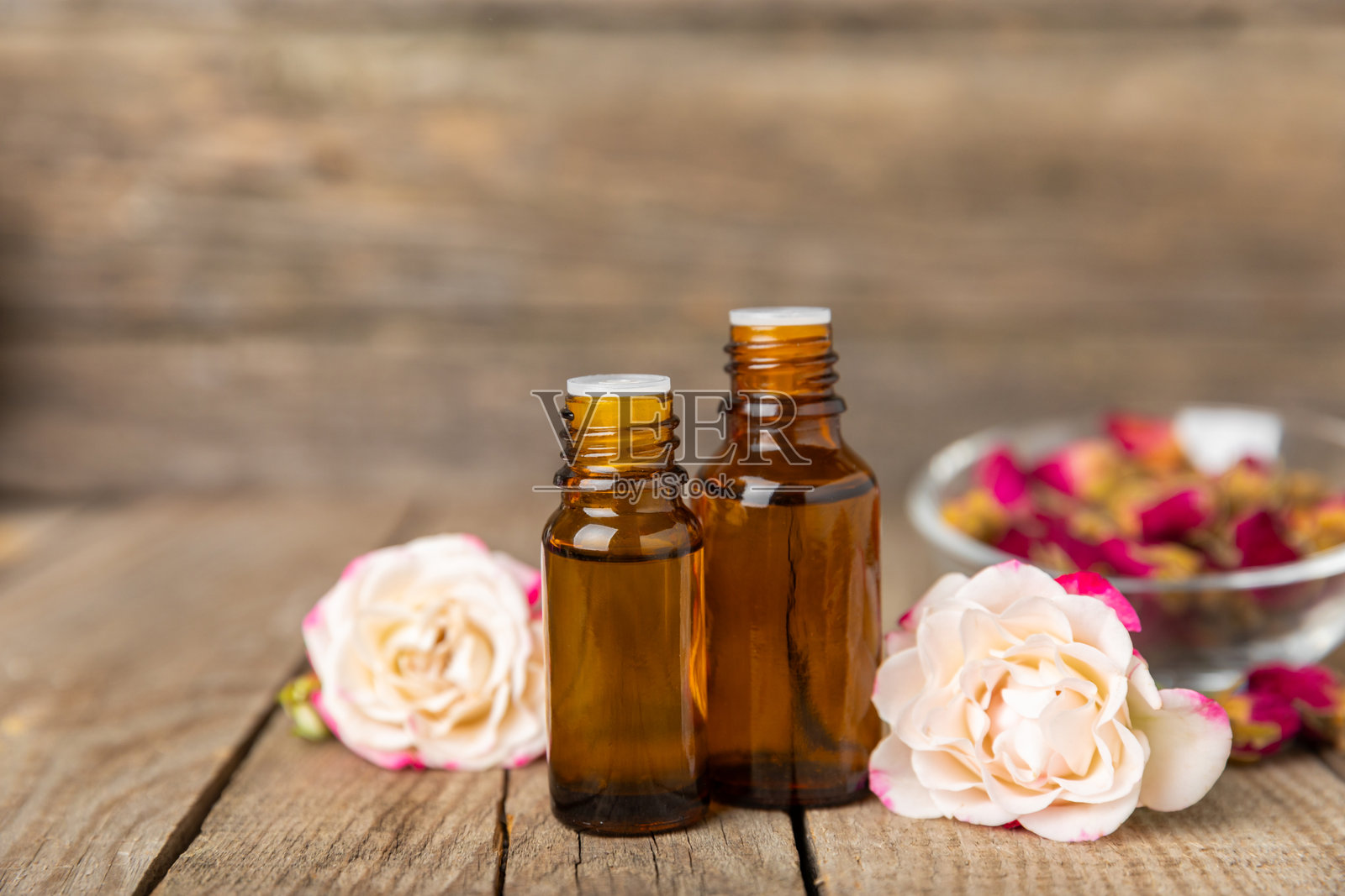 玫瑰精油在纹理背景上。玫瑰和一瓶玫瑰香水。芳香疗法治疗。美容概念。水疗程序。天然有机油。抗压、排毒放松。文本位置。照片摄影图片