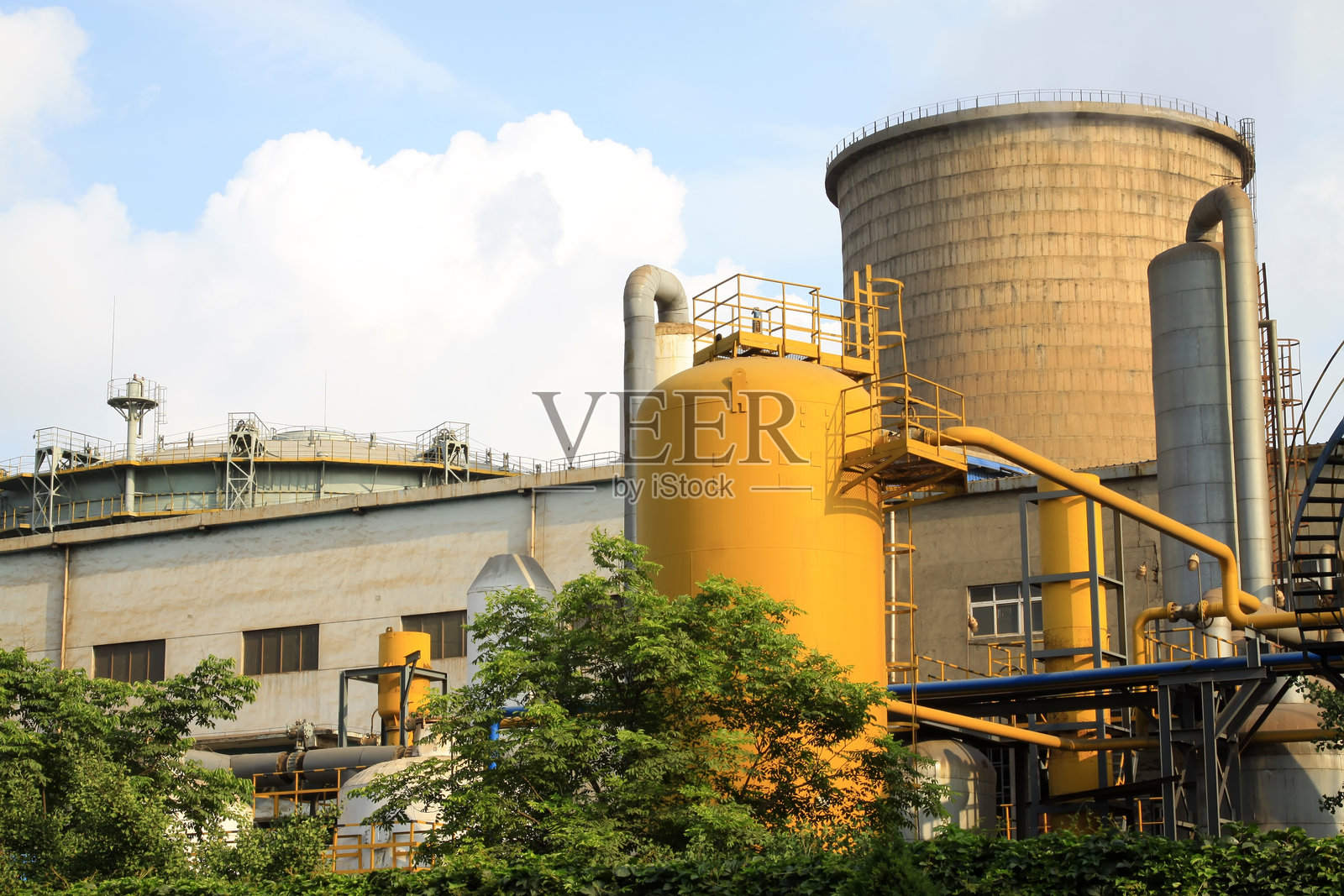 工厂里的黄色金属罐和冷却塔照片摄影图片