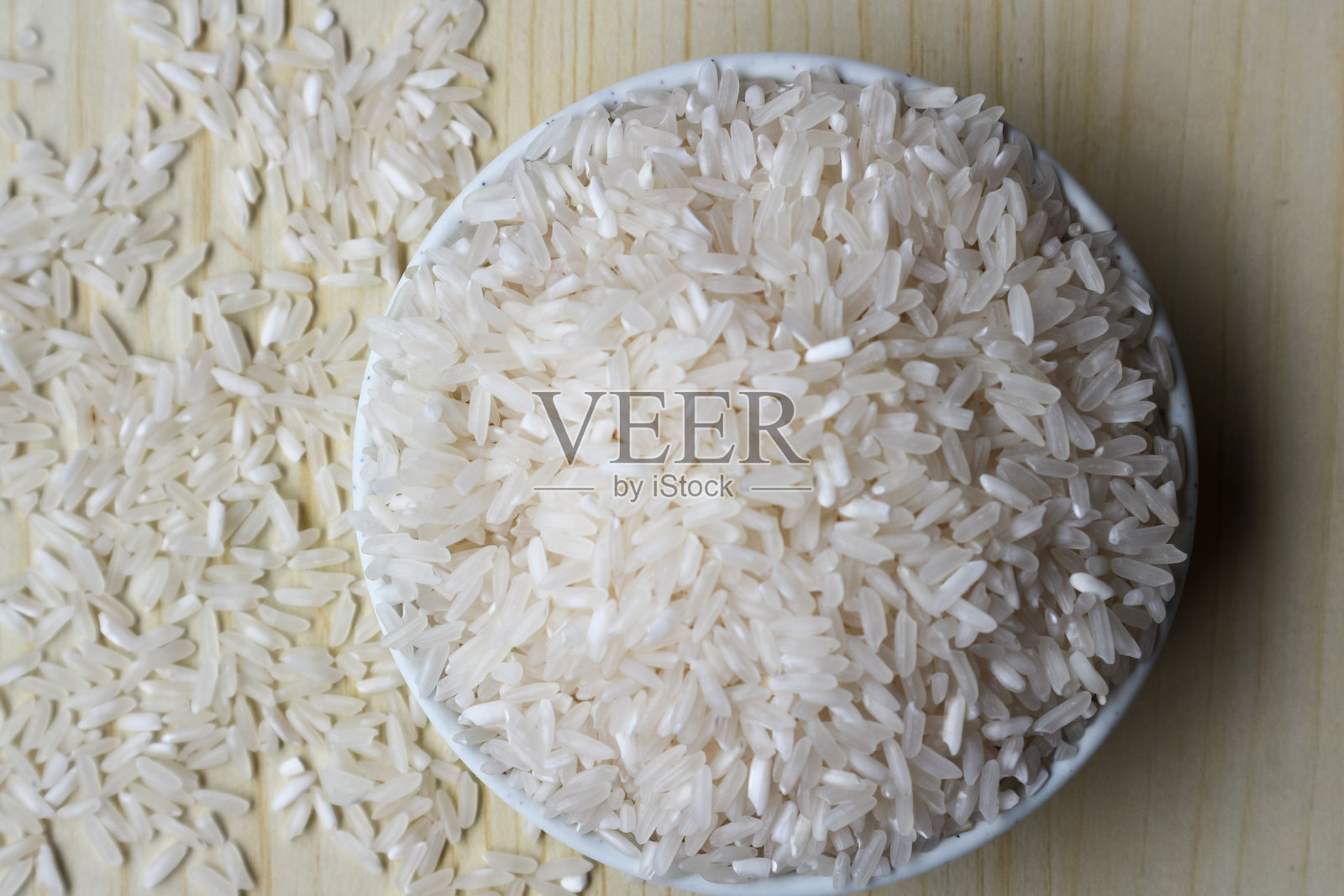 白色碗中的生米，背景为木质表面照片摄影图片
