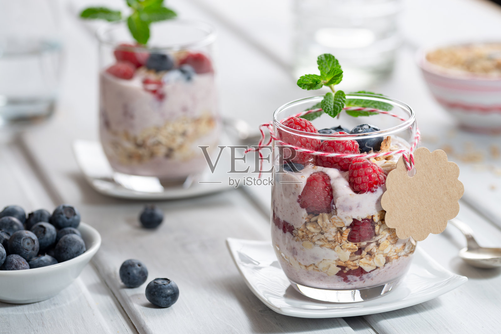 健康甜点 - 玻璃杯中分层的覆盆子与酸奶，旁边有一个纸板标志用于文字照片摄影图片