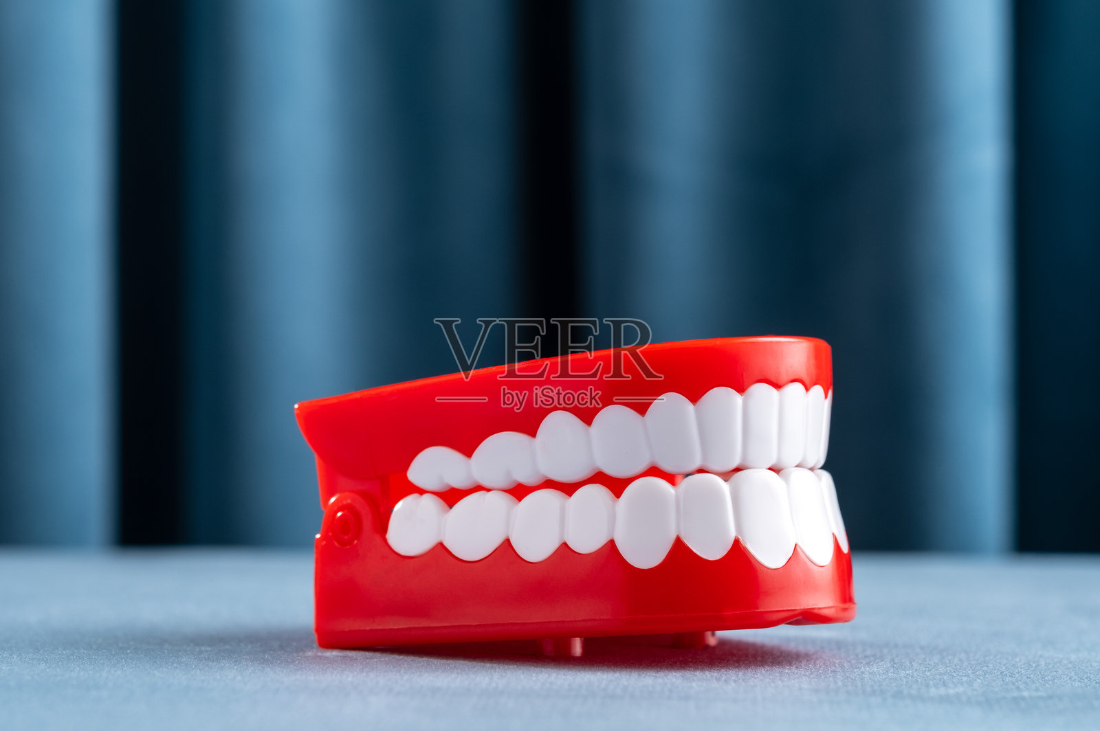 一位模特站在蓝色窗帘的背景前。照片摄影图片