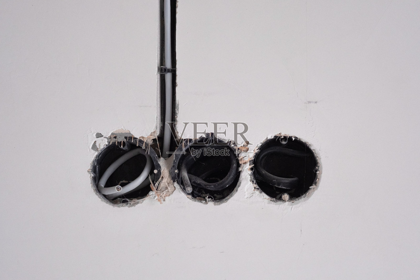 白色墙面上的公用设施孔，黑色管道和多个开口照片摄影图片