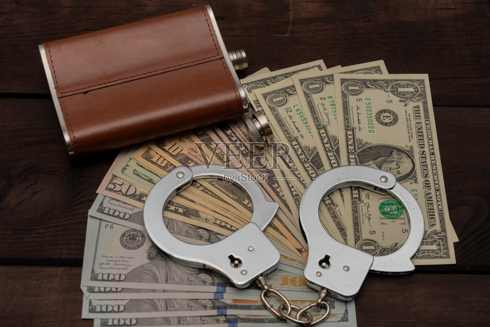 非法收入及其后果：一捆捆美元、手铐和酒精。照片摄影图片
