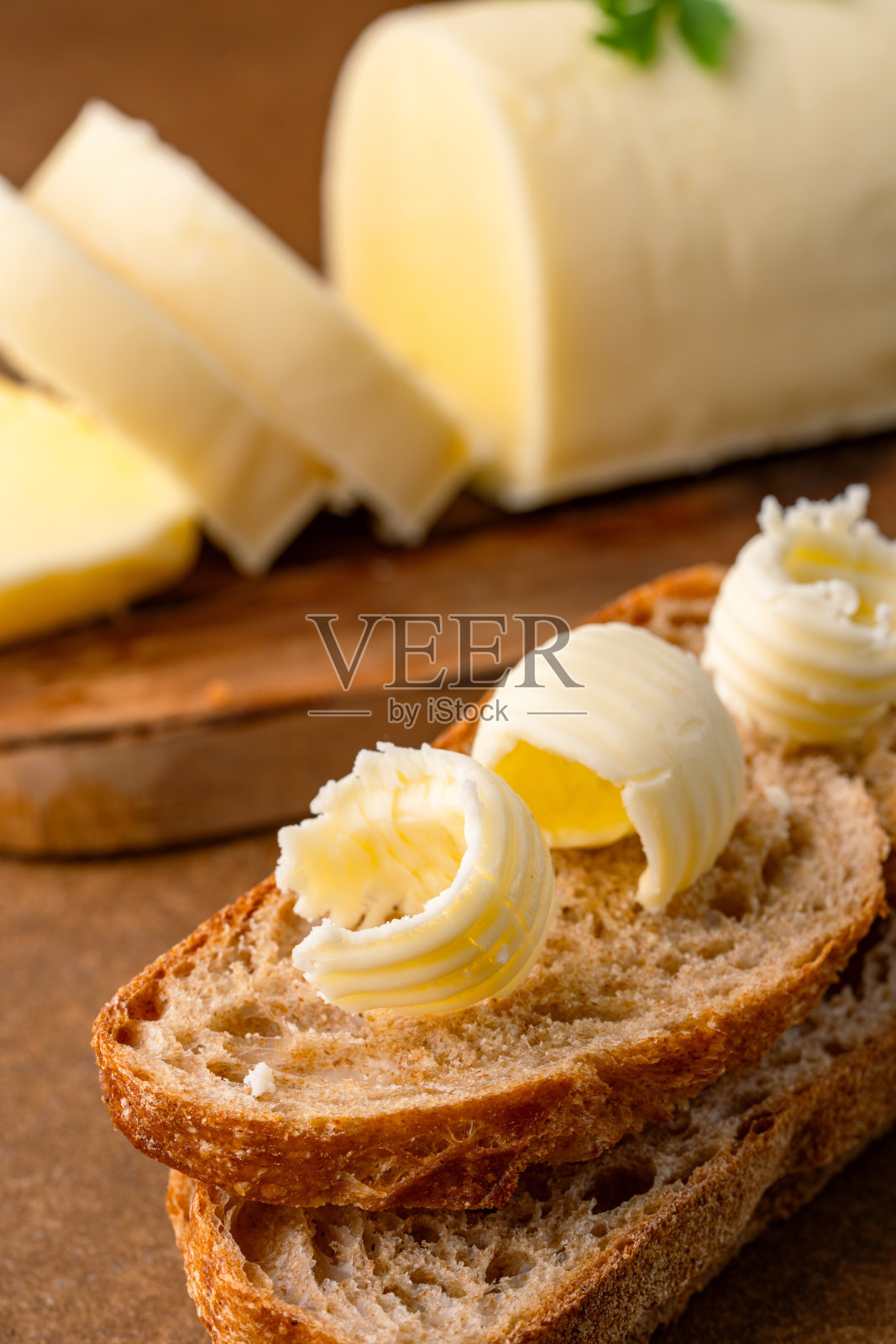 在棕色复古背景下，增添风味的黄油，适合早餐使用。照片摄影图片