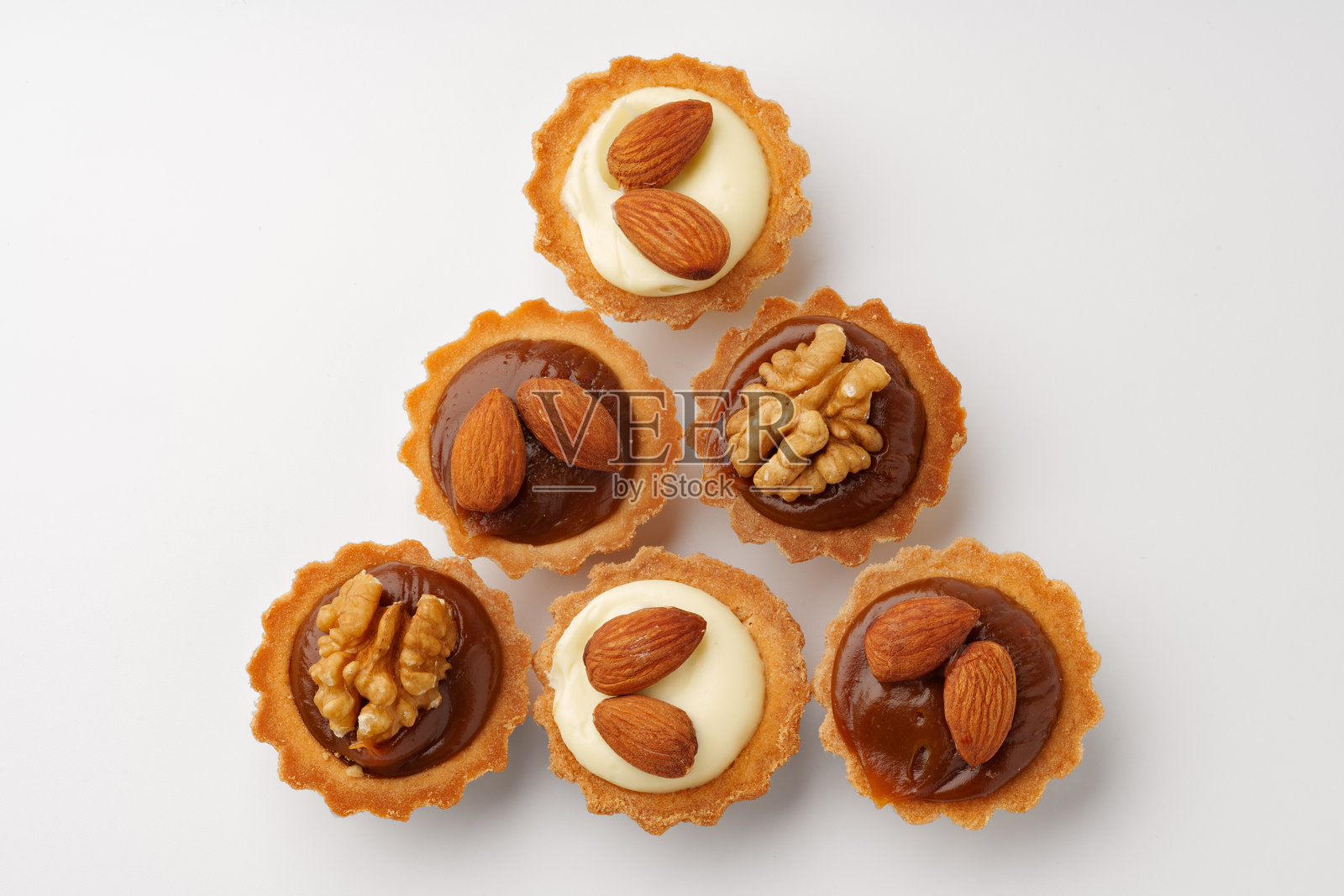 各种填充焦糖和坚果的酥皮小塔，背景为白色，准备在聚会上供应照片摄影图片