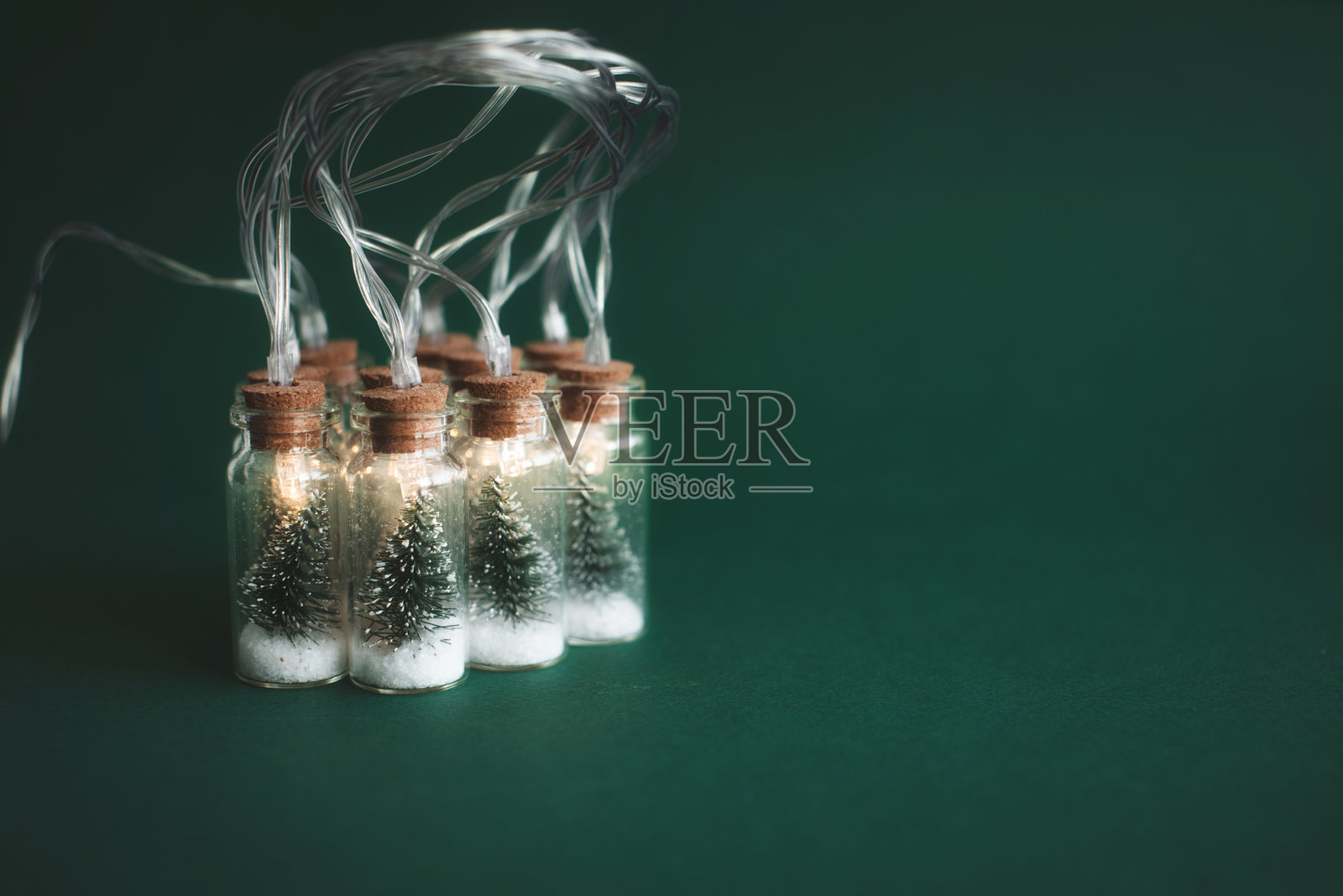 节日花环的玻璃罐与圣诞树和雪在绿色的背景。圣诞节和新年的概念照片摄影图片