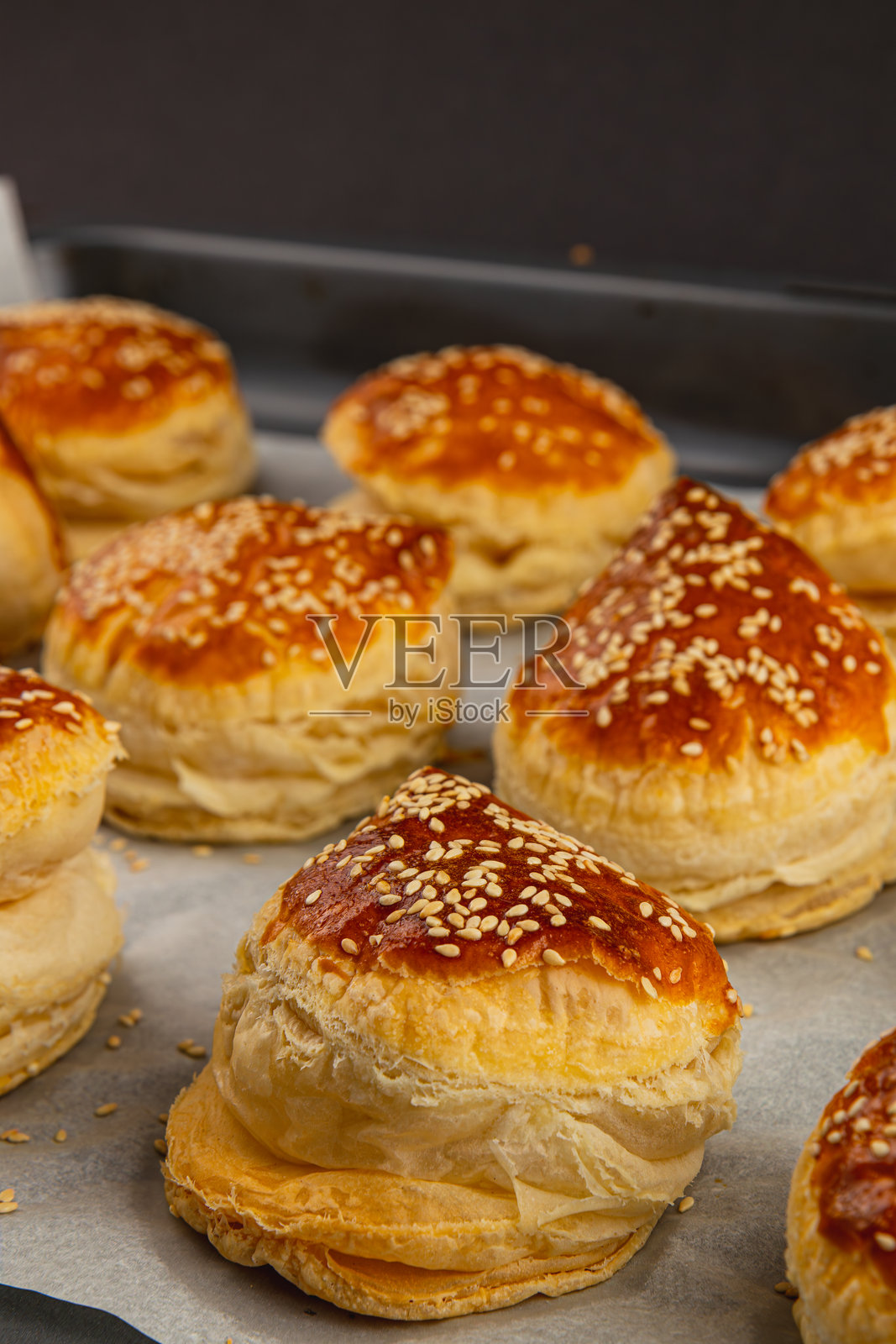 新鲜出炉的糕点，金黄色的外皮上撒有芝麻，正在展示中照片摄影图片