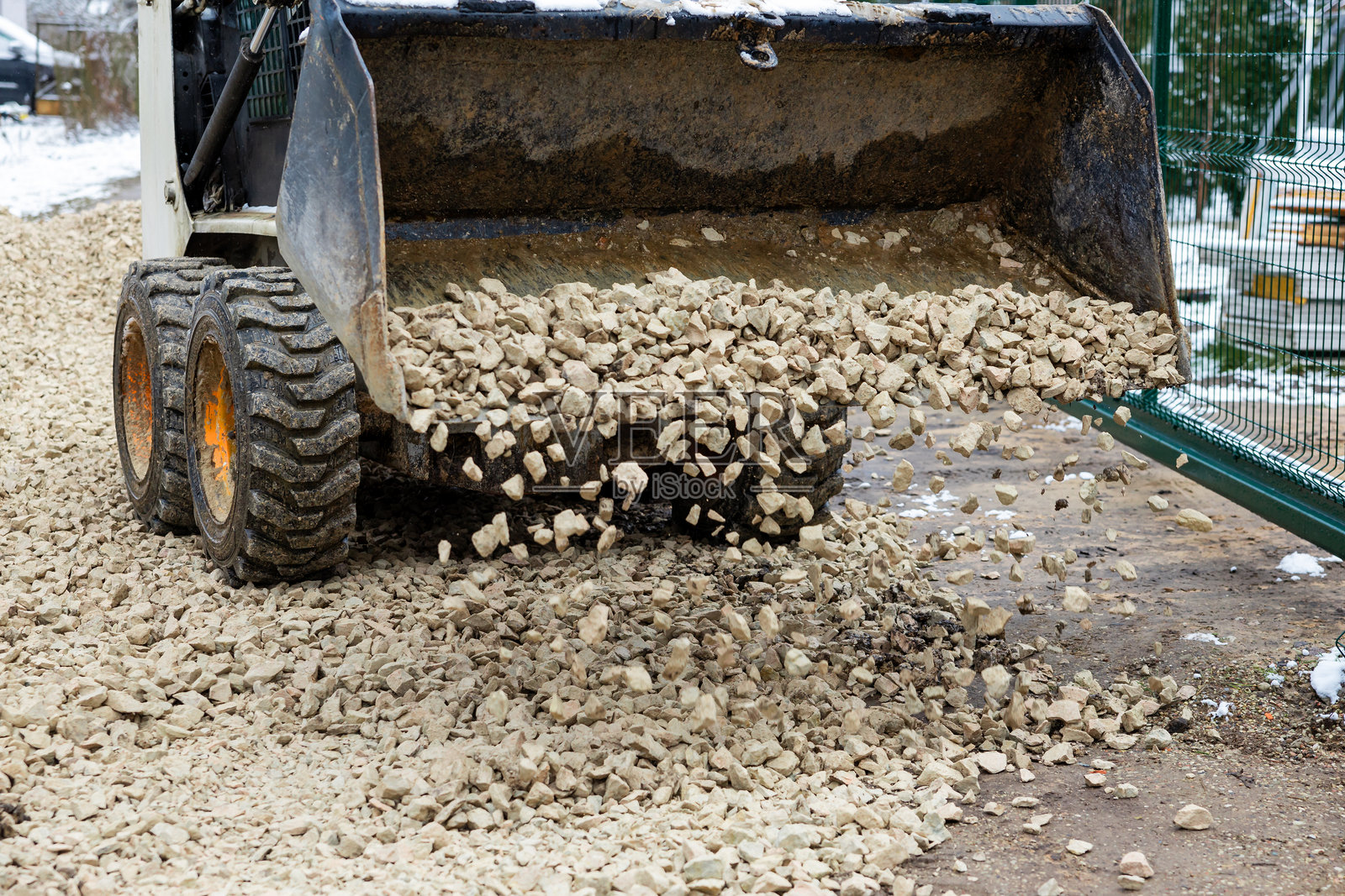 建筑车辆在覆盖雪的土壤表面倾倒石头照片摄影图片