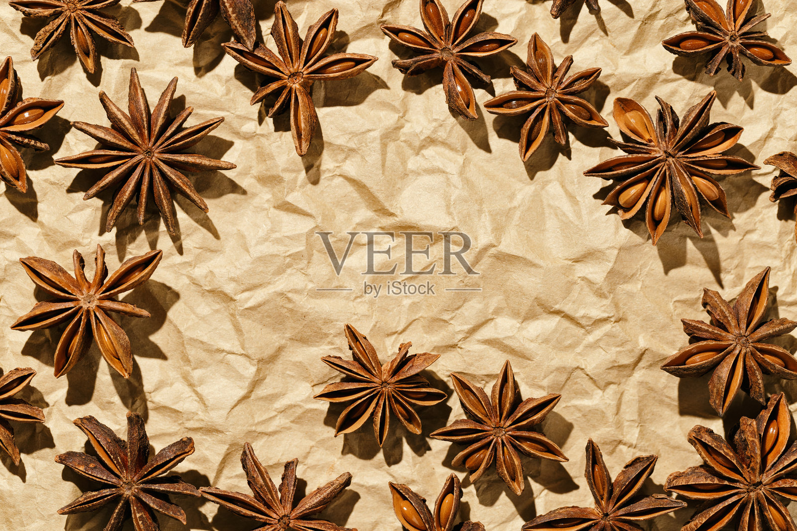 八角星框架背景，俯视特写微距摄影，香料干八角种子放在皱褶的烘焙纸上，自然有机调料纹理，食品图案，棕色米色单色调照片摄影图片