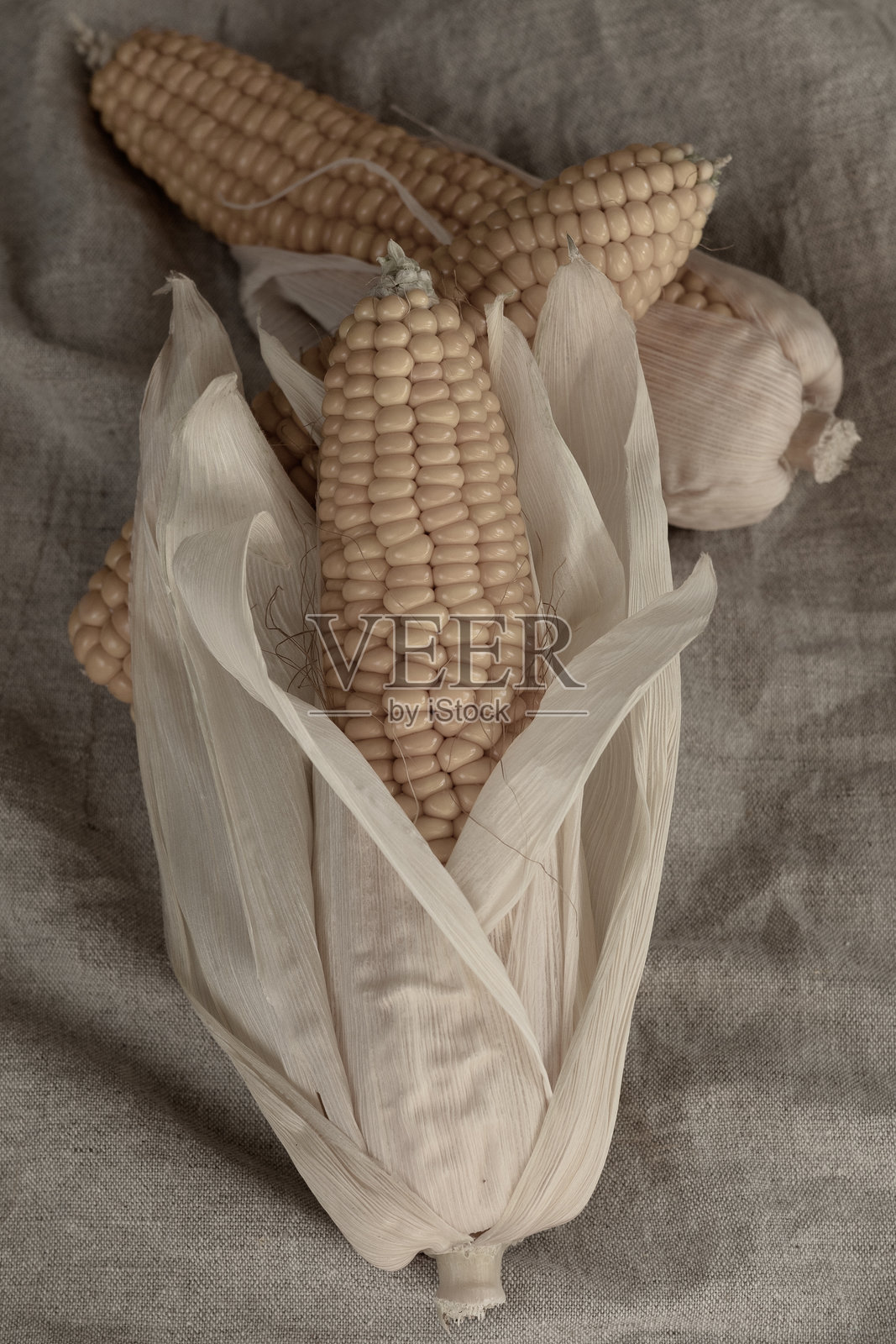 新鲜的玉米棒放在麻布背景上。调色处理。照片摄影图片