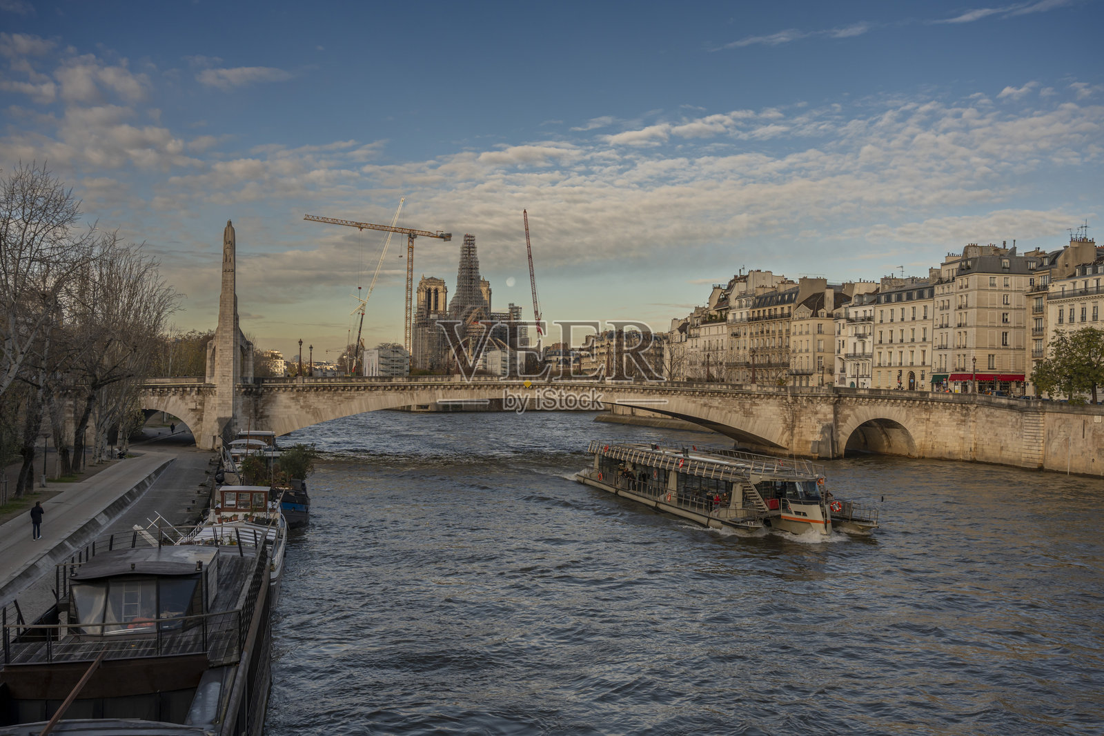 法国巴黎——2023年11月30日:巴黎圣母院。由脚手架、新尖塔、萨利桥和奥斯特里茨桥上的月亮组成的修复现场全景照片摄影图片