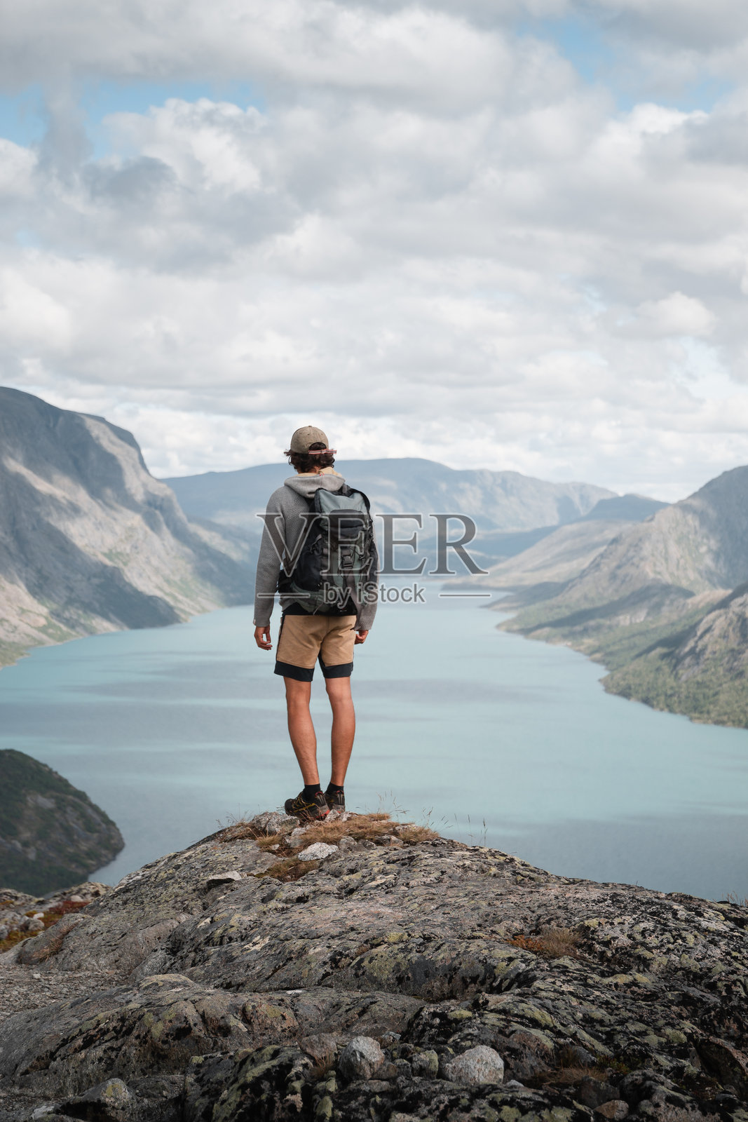男子站在挪威峡湾上，享受宁静的徒步时光，俯瞰壮丽的风景。照片摄影图片