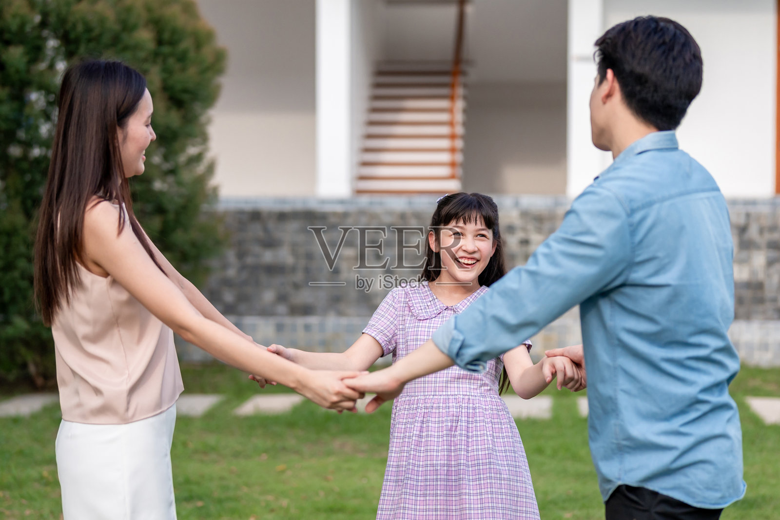 亚洲父母在花园里与小女儿玩耍。幸福的家庭，迷人的夫妻和小女孩感到放松，享受在家后院度过的时光。家庭关系概念照片摄影图片