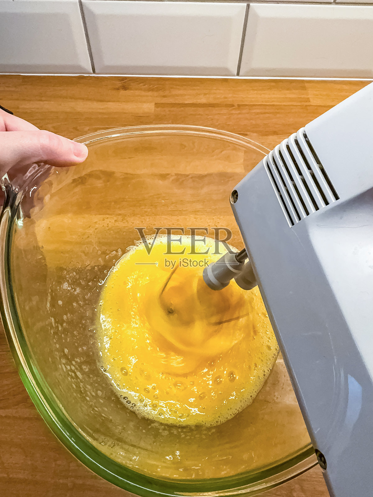 手握搅拌碗，电动搅拌器在厨房中搅打蛋黄照片摄影图片