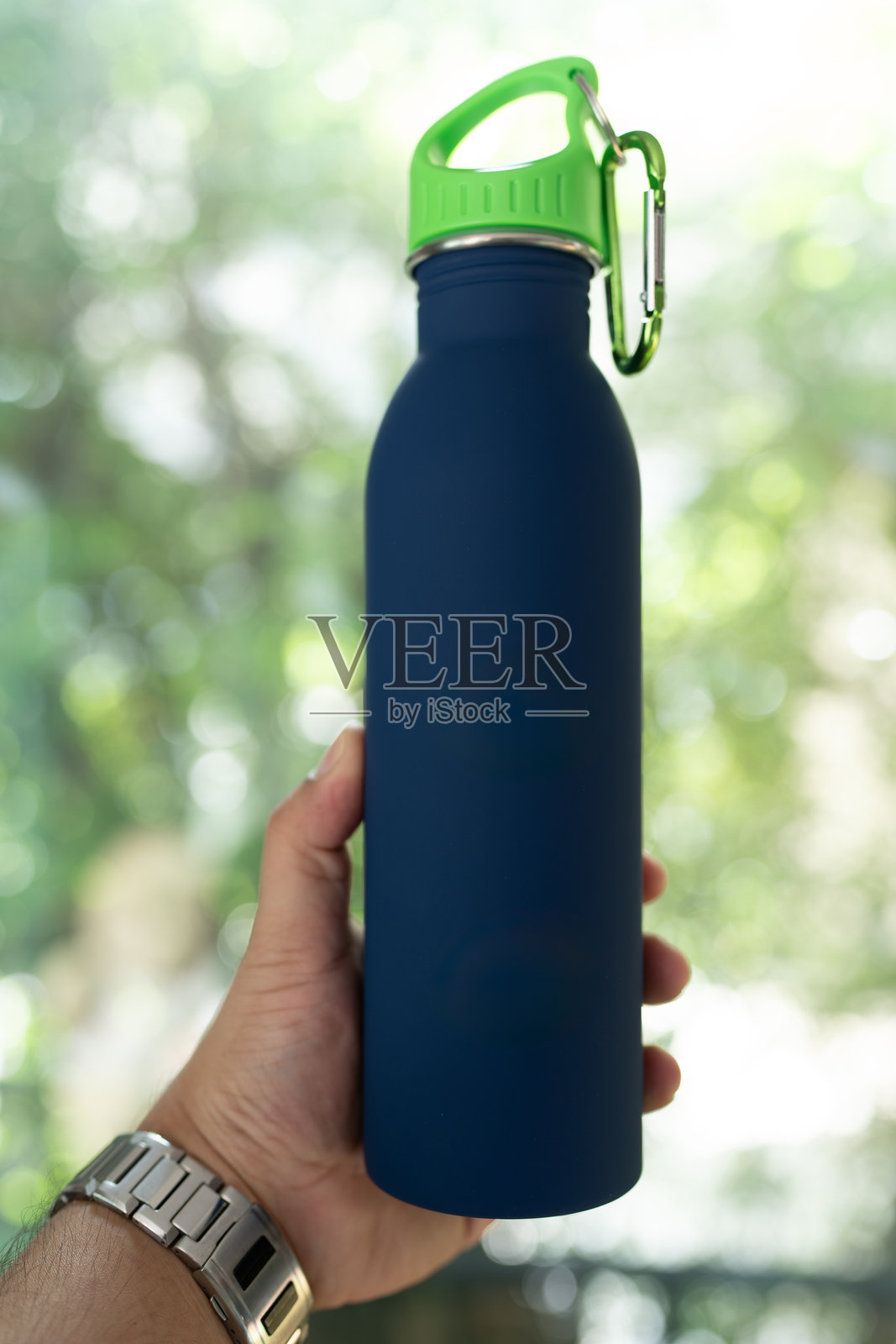 男性手握蓝色可重复使用的不锈钢水瓶照片摄影图片