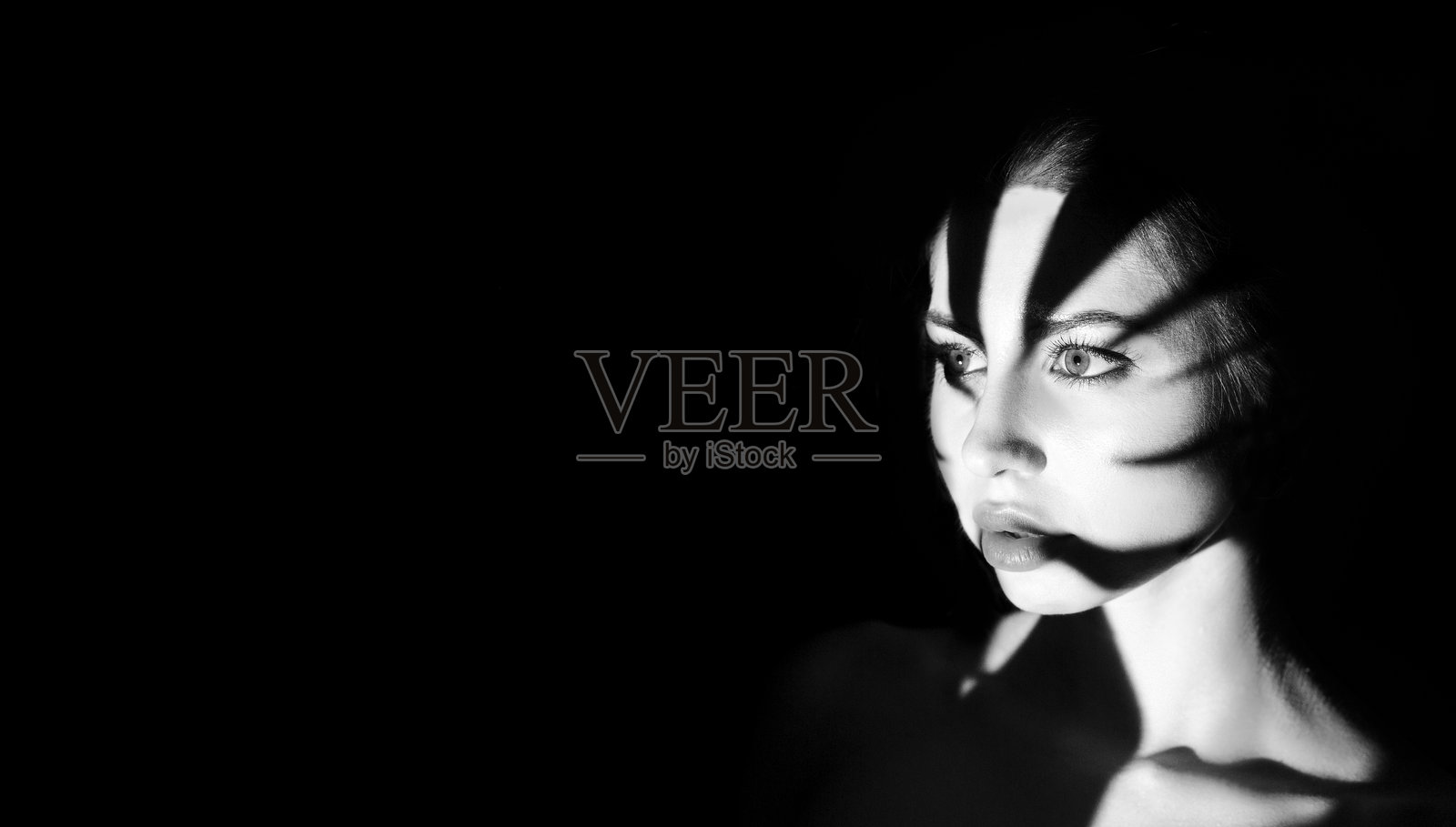 戏剧性的黑白肖像，展现女性脸上的强烈阴影照片摄影图片