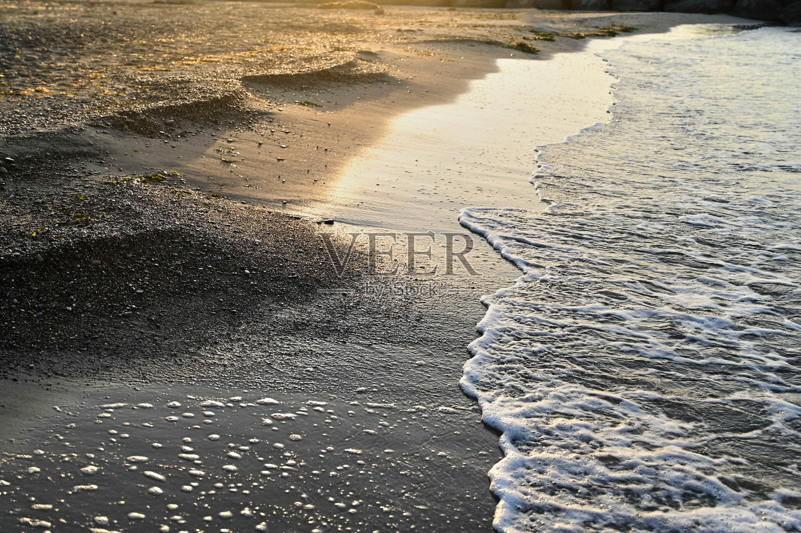 宁静的海岸线在日落时分展现出温柔的波浪和柔软的沙滩，营造出一个宁静的海滩度假胜地。照片摄影图片