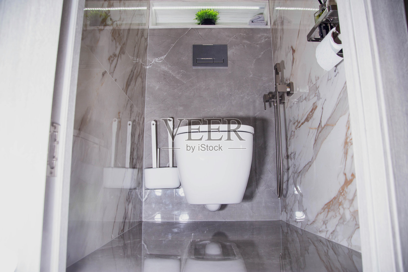 这是一间现代浴室的内部装修，有一个悬挂式马桶，一个卫生淋浴间，墙上贴着陶瓷瓷砖。二极管带的壁龛照片摄影图片