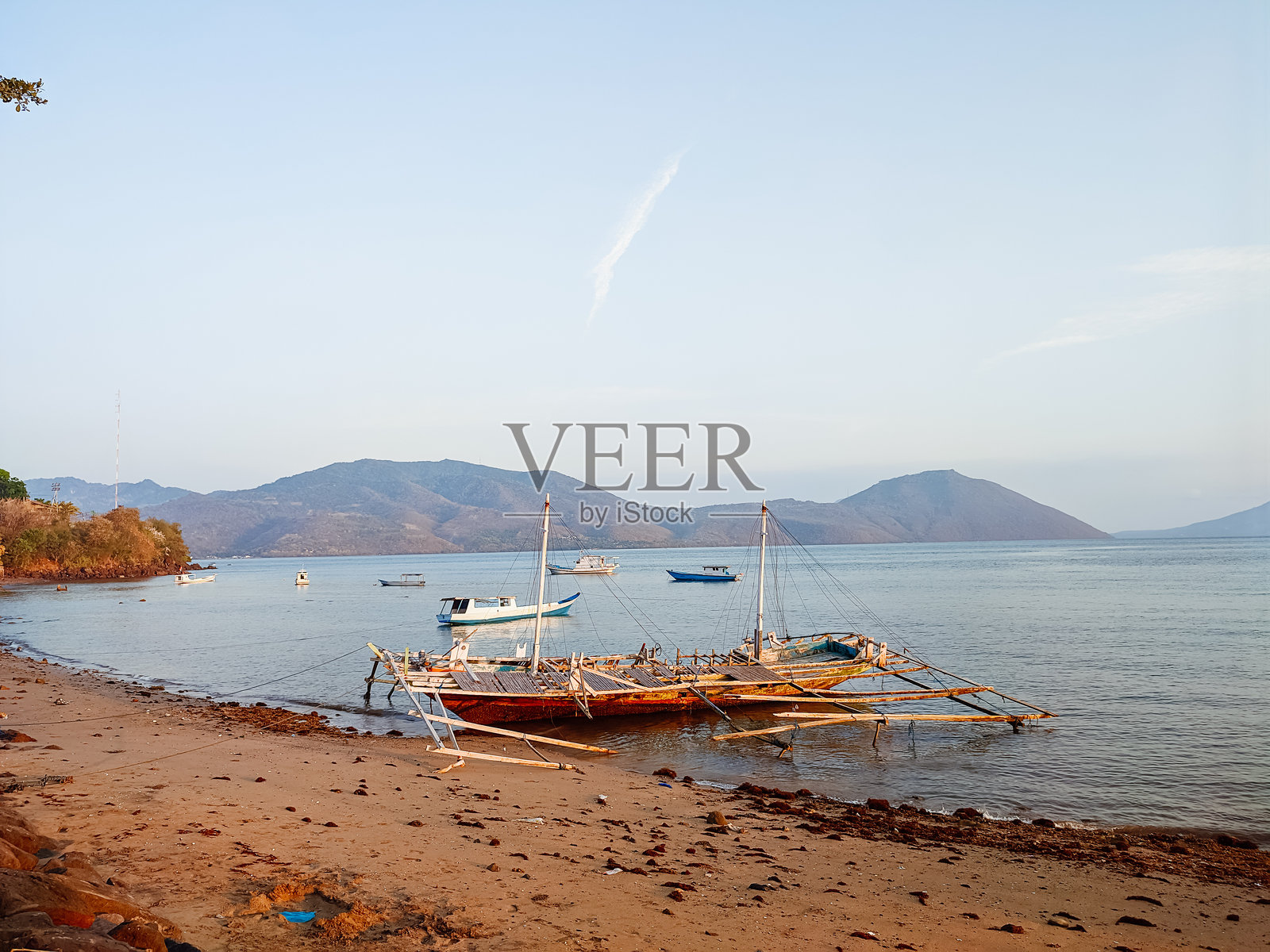 下午的海滩上气氛很浓，有渔船停泊，太阳开始下山照片摄影图片