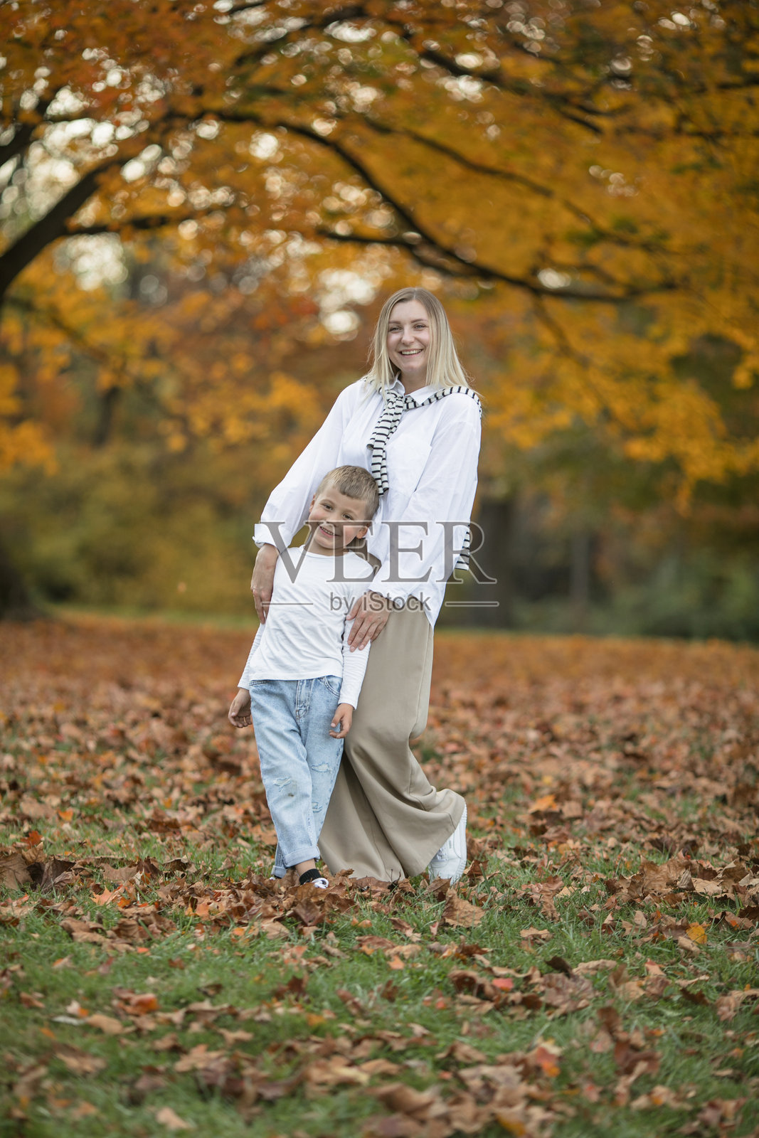 母亲节，爱家人。秋天一家人在大自然中散步。母亲和孩子拥抱温柔照片摄影图片