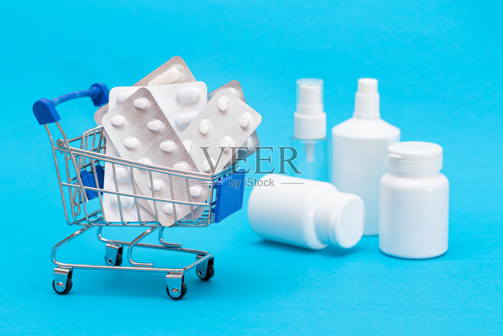 蓝色背景的购物车里的药丸和胶囊照片摄影图片