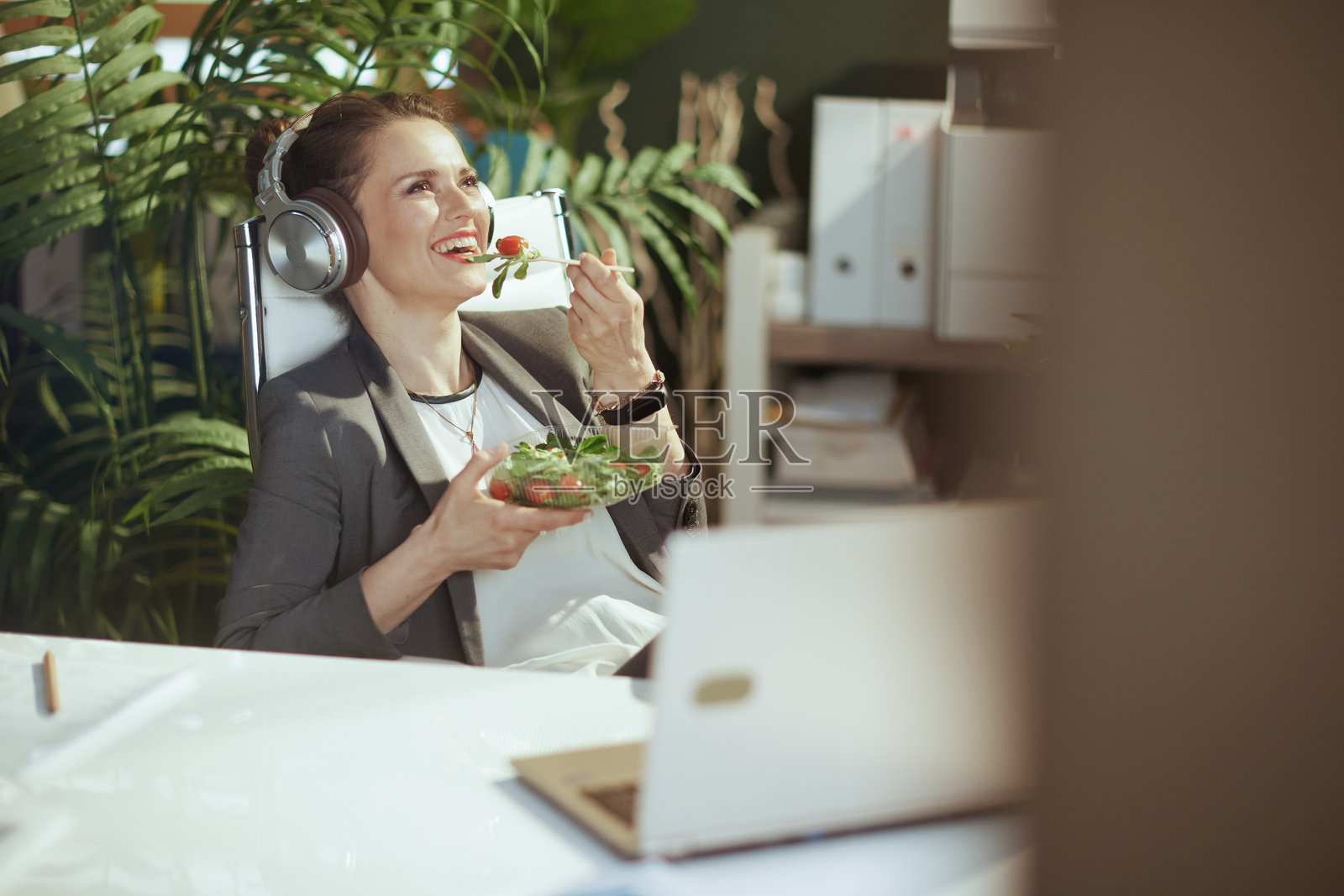 女会计一边吃沙拉一边听音乐照片摄影图片